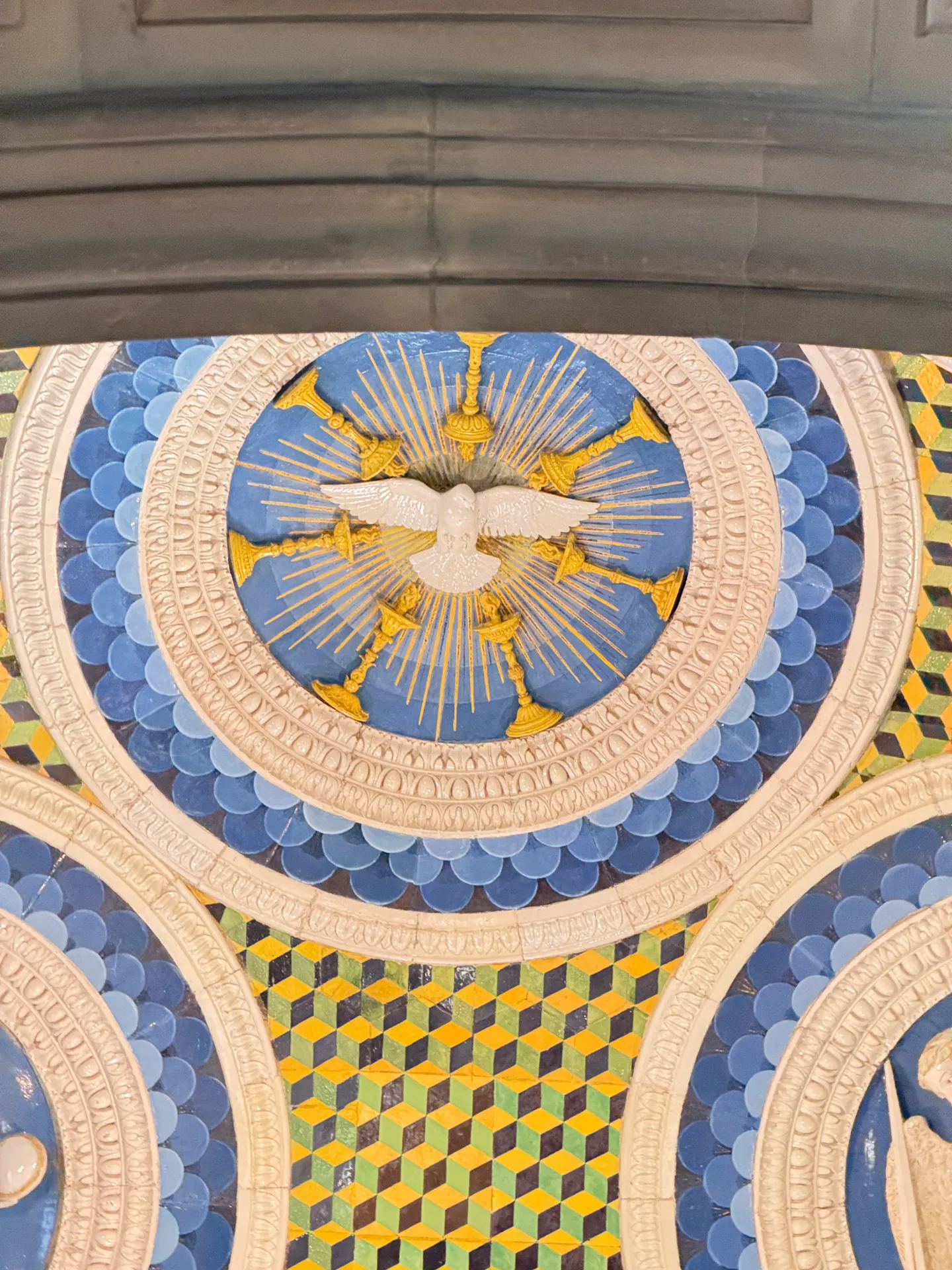 The dove of the Holy Spirit in glazed terracotta on a blue ground, one roundel of the chapel ceiling seen close.