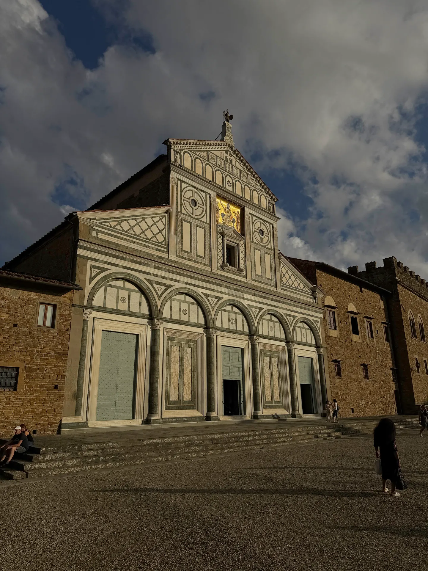 The flank of San Miniato al Monte in evening sun, the fortified monastery block and the truncated campanile behind it.