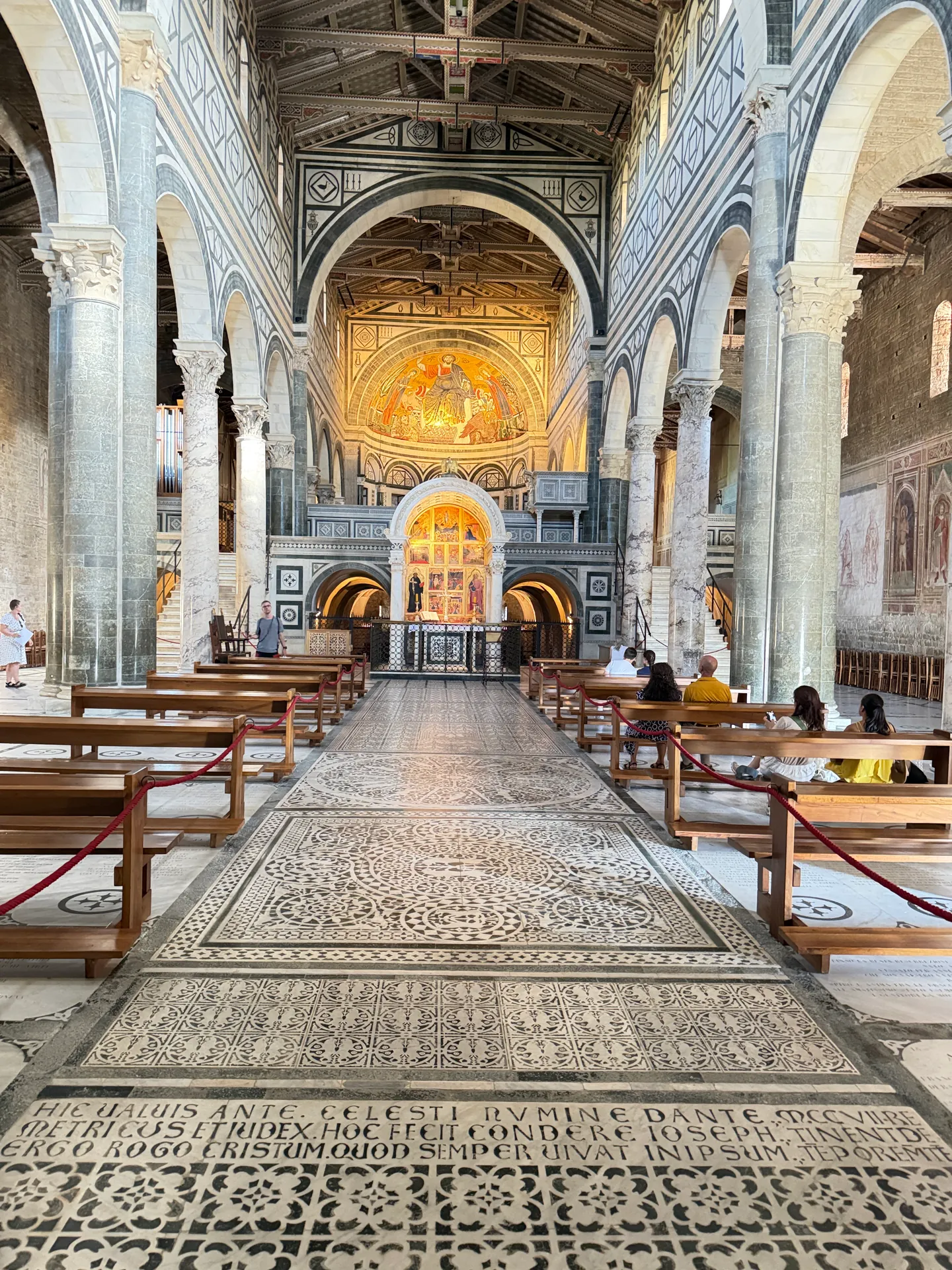 The nave of San Miniato on axis, the inlaid pavement running to the raised choir and the gold apse mosaic.