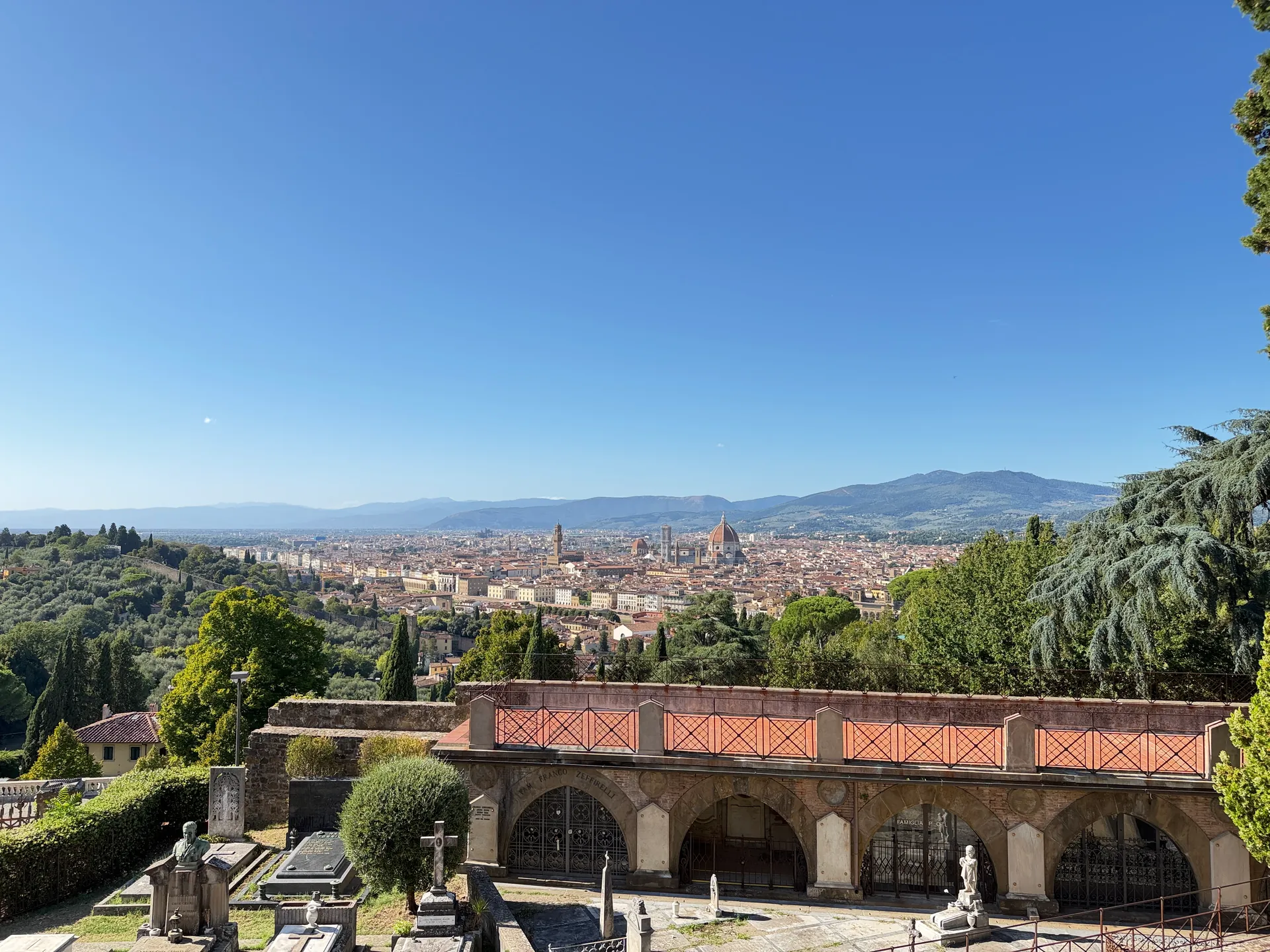 The arcade and tombs of the Porte Sante cemetery seen from above, with Florence beyond.