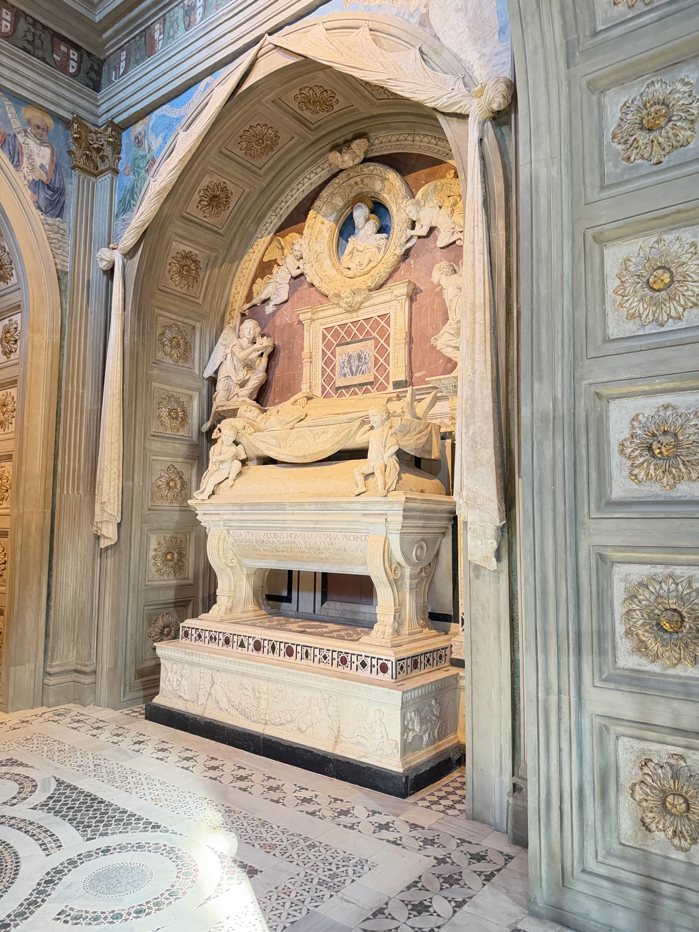 Rossellino's tomb of the Cardinal of Portugal under its carved marble drapery arch.