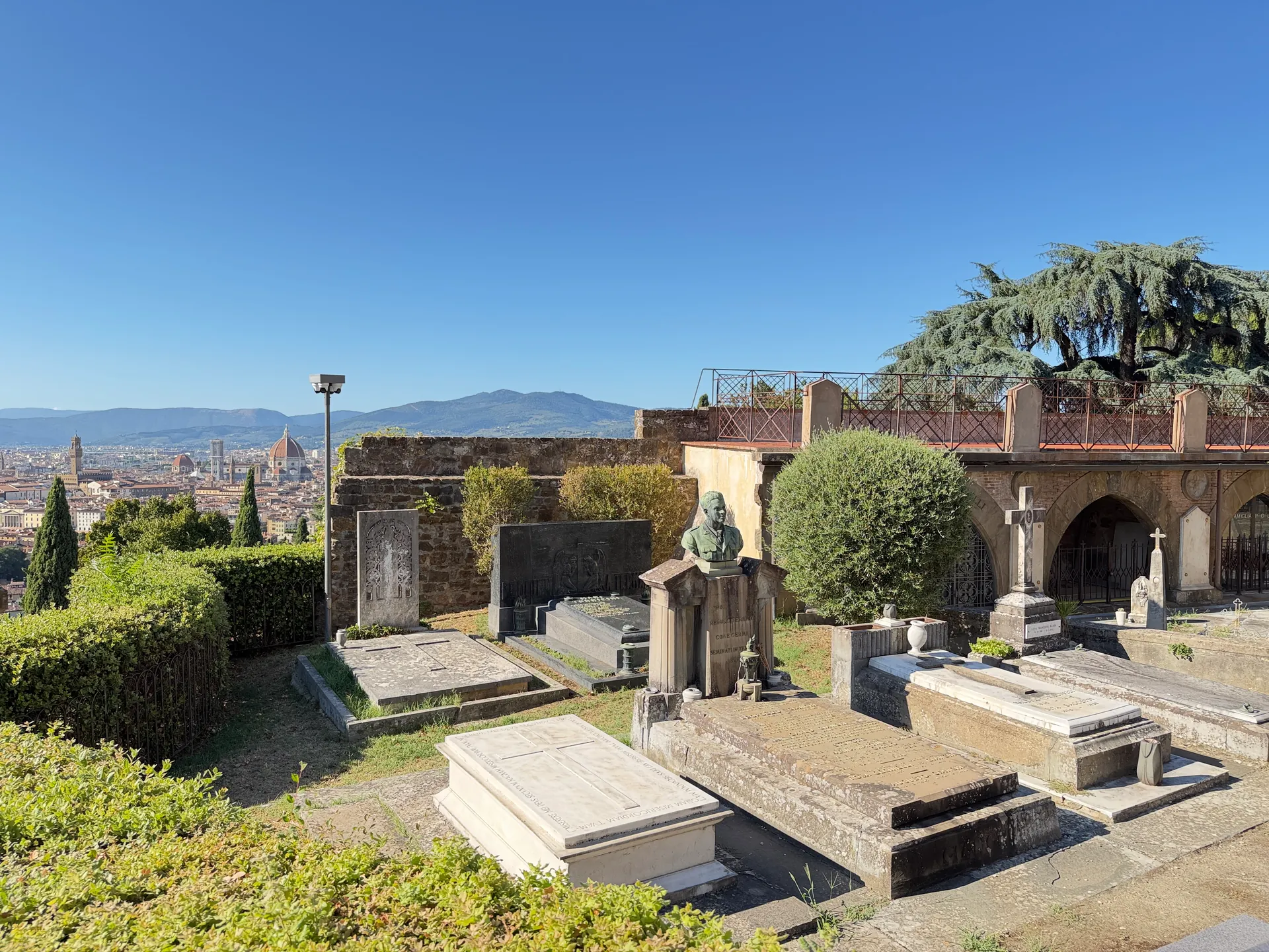 A terrace of tomb monuments in the Porte Sante cemetery, the Duomo rising in the distance.
