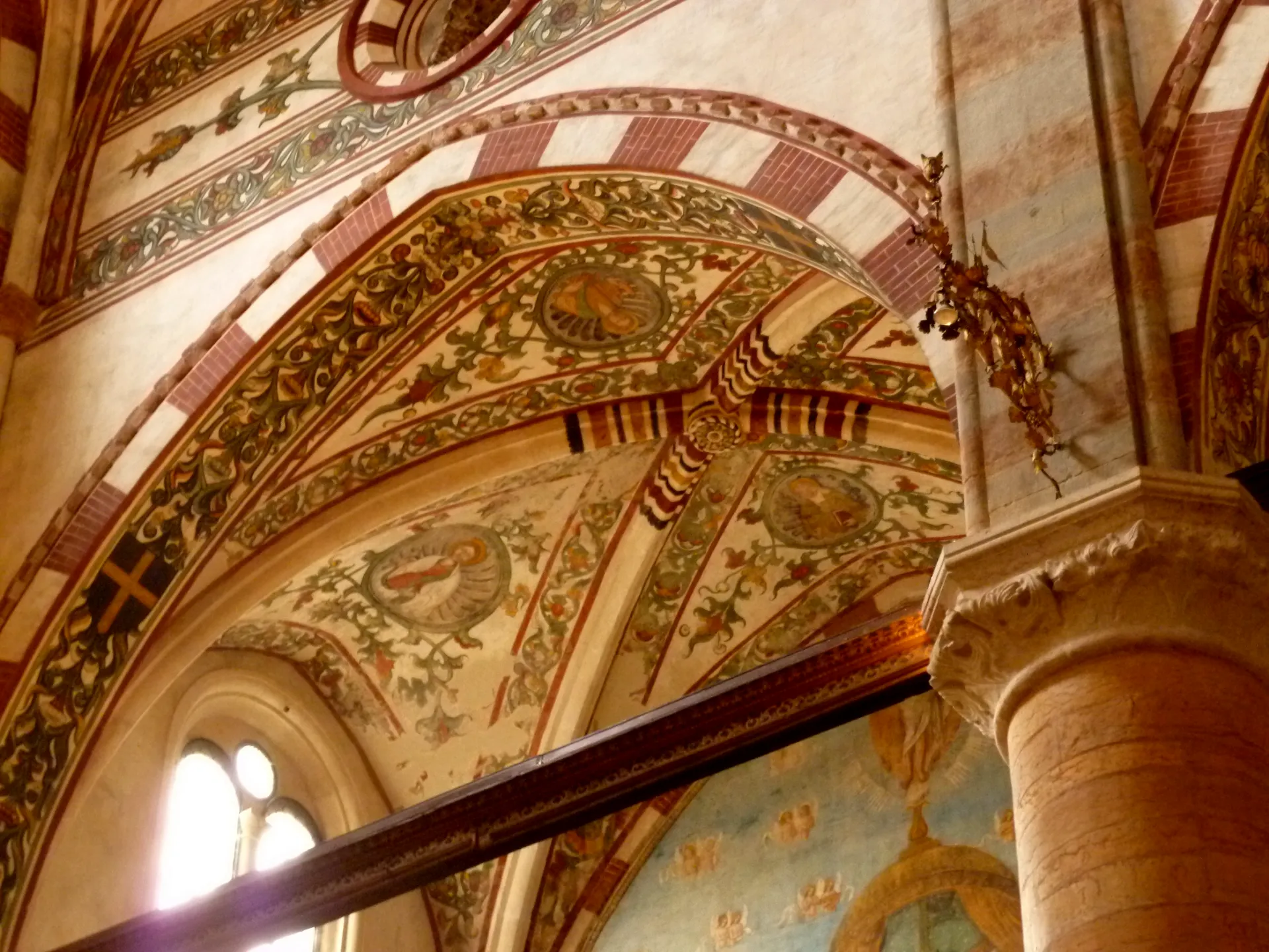 Frescoed vaulting meeting a carved capital inside Santa Anastasia in Verona