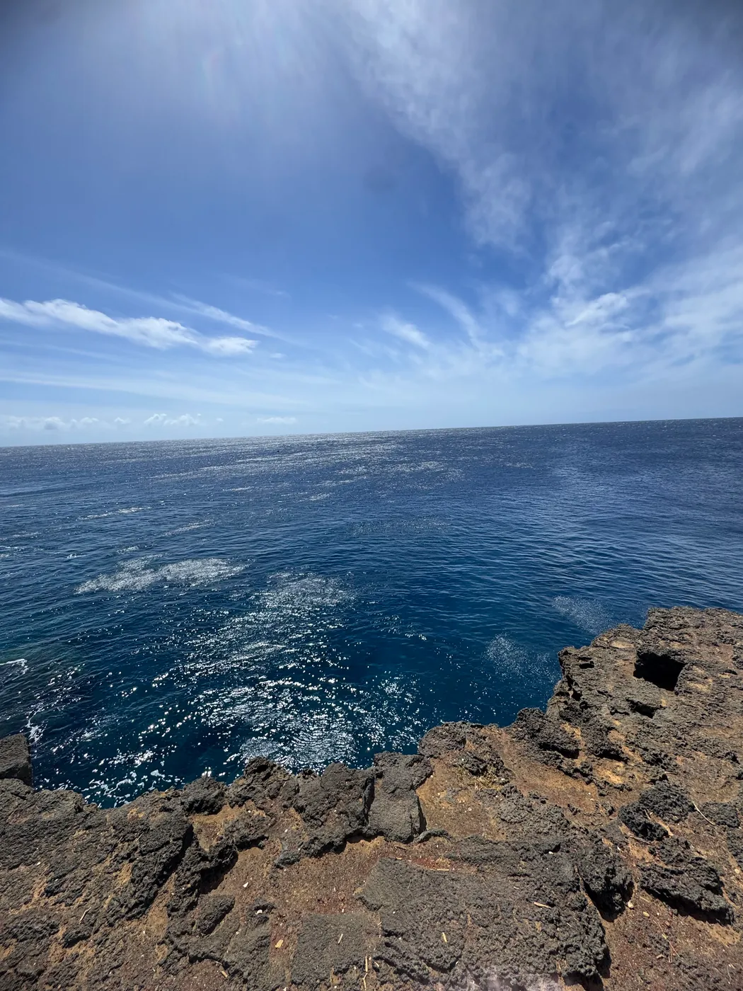 A square mooring hole cut in a lava shelf above deep blue water at Ka Lae