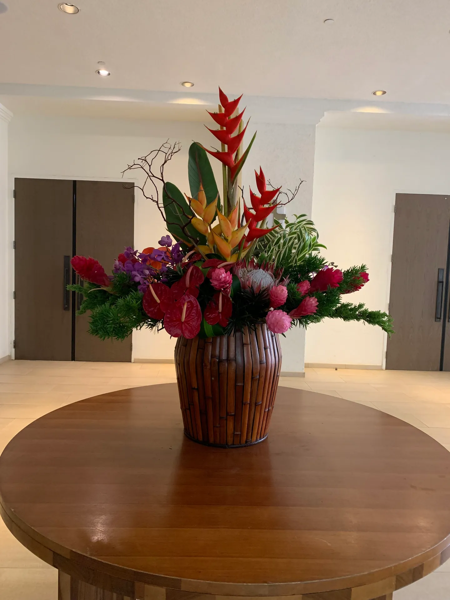 Tropical flower arrangement with heliconia on a round wooden lobby table