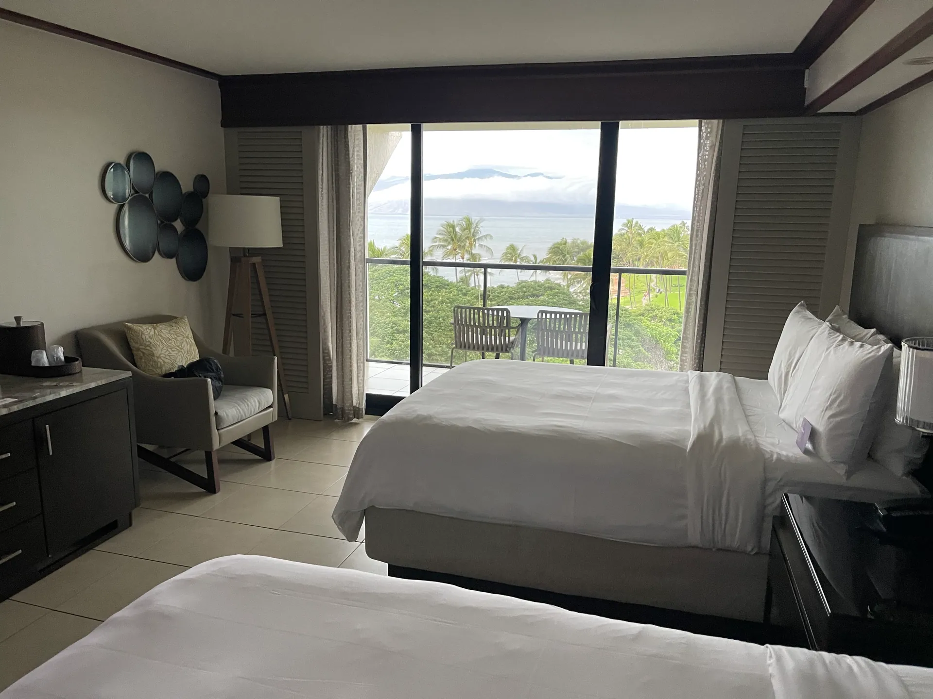Hotel room with a bed facing a window over treetops to distant mountains