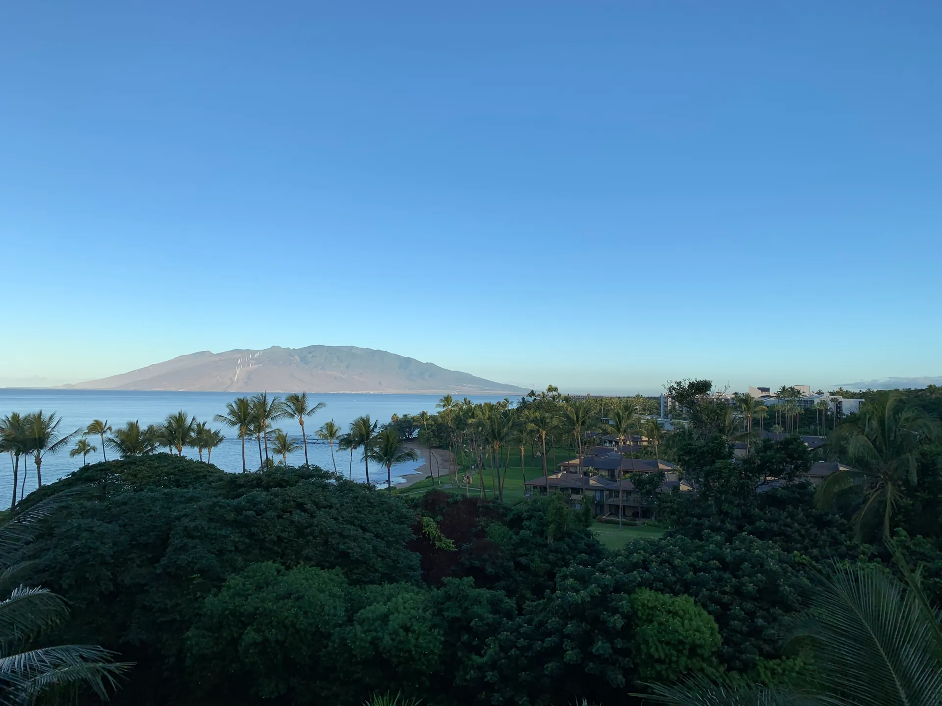 Early morning view from a room over gardens to Ulua Beach and mountains across the water