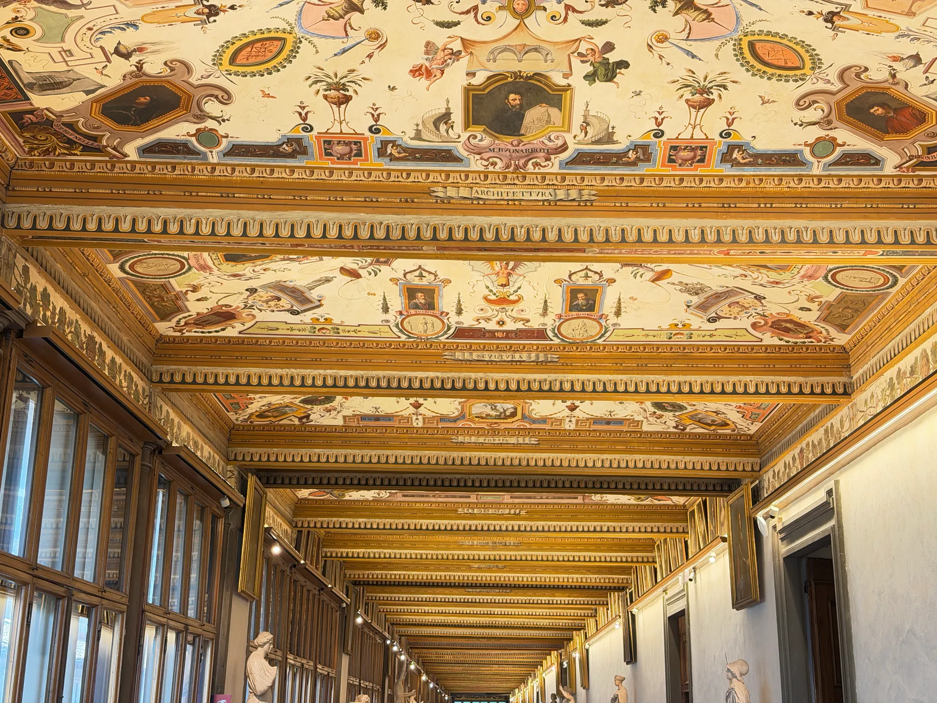A gallery corridor of the Uffizi running away in perspective, antique marbles ranged along both walls.