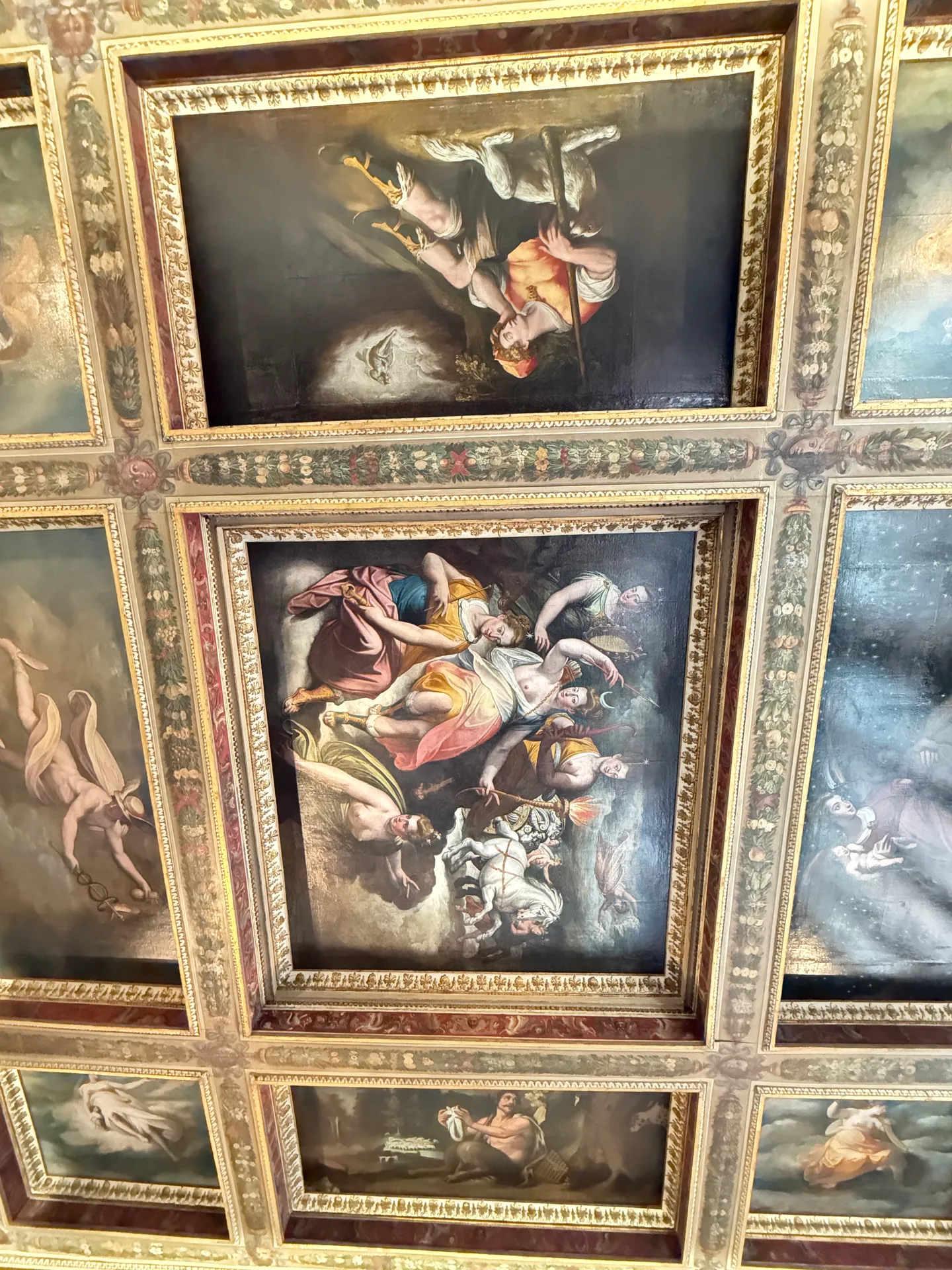 A gilded coffered ceiling in the Uffizi, painted canvases set into its compartments.