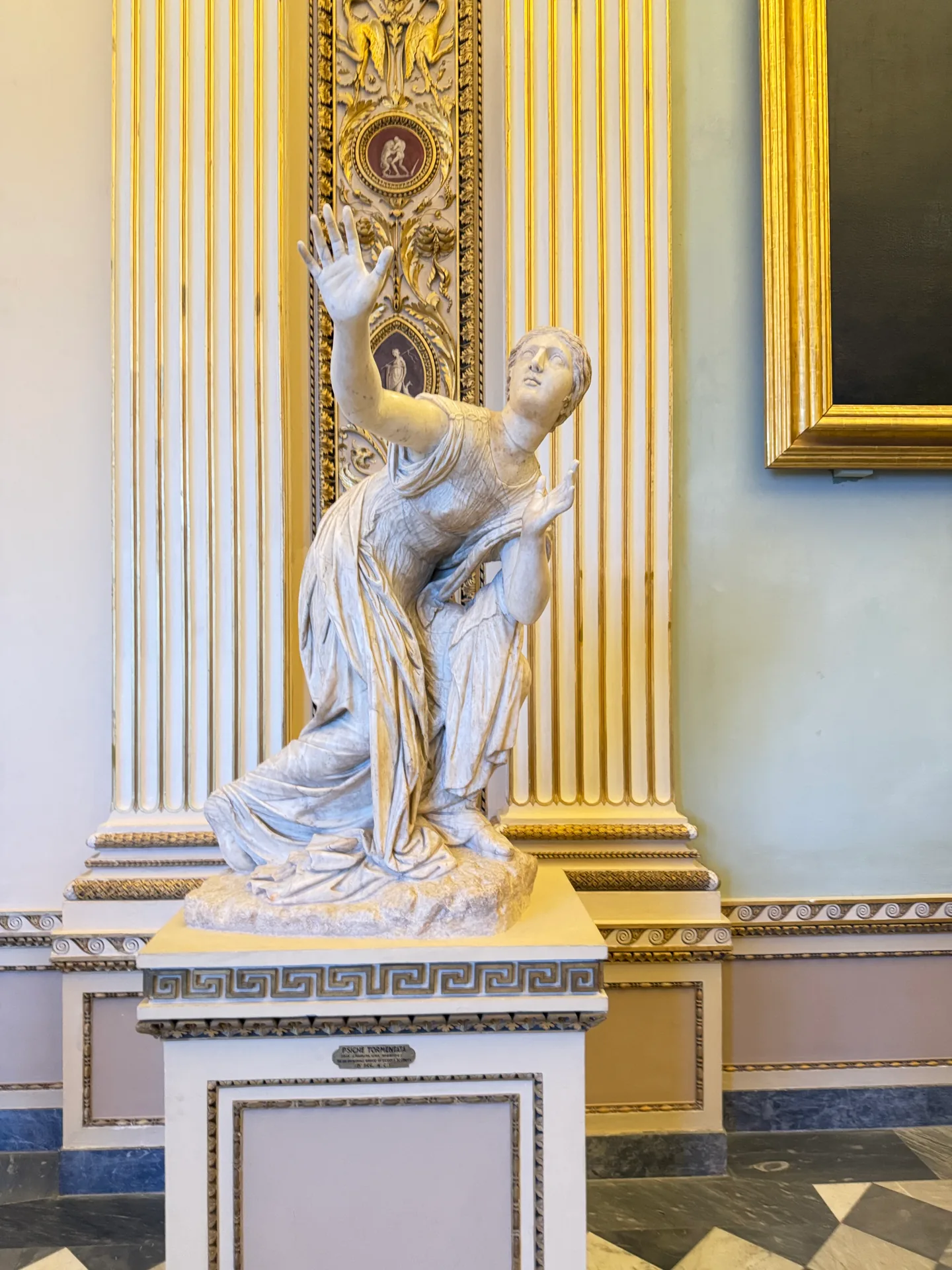 A kneeling daughter of Niobe with her arms raised, complete on her plinth.