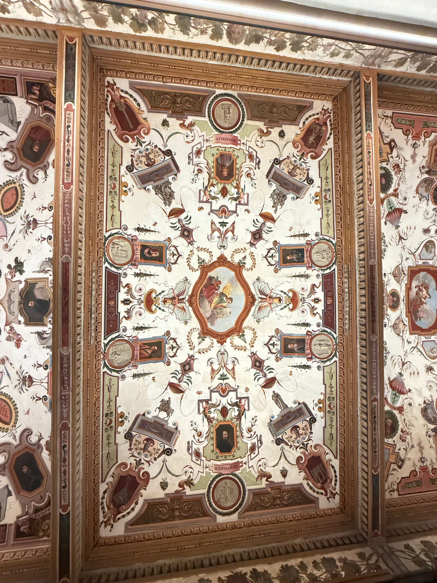 A painted medallion set in scrollwork on a corridor ceiling of the Uffizi.
