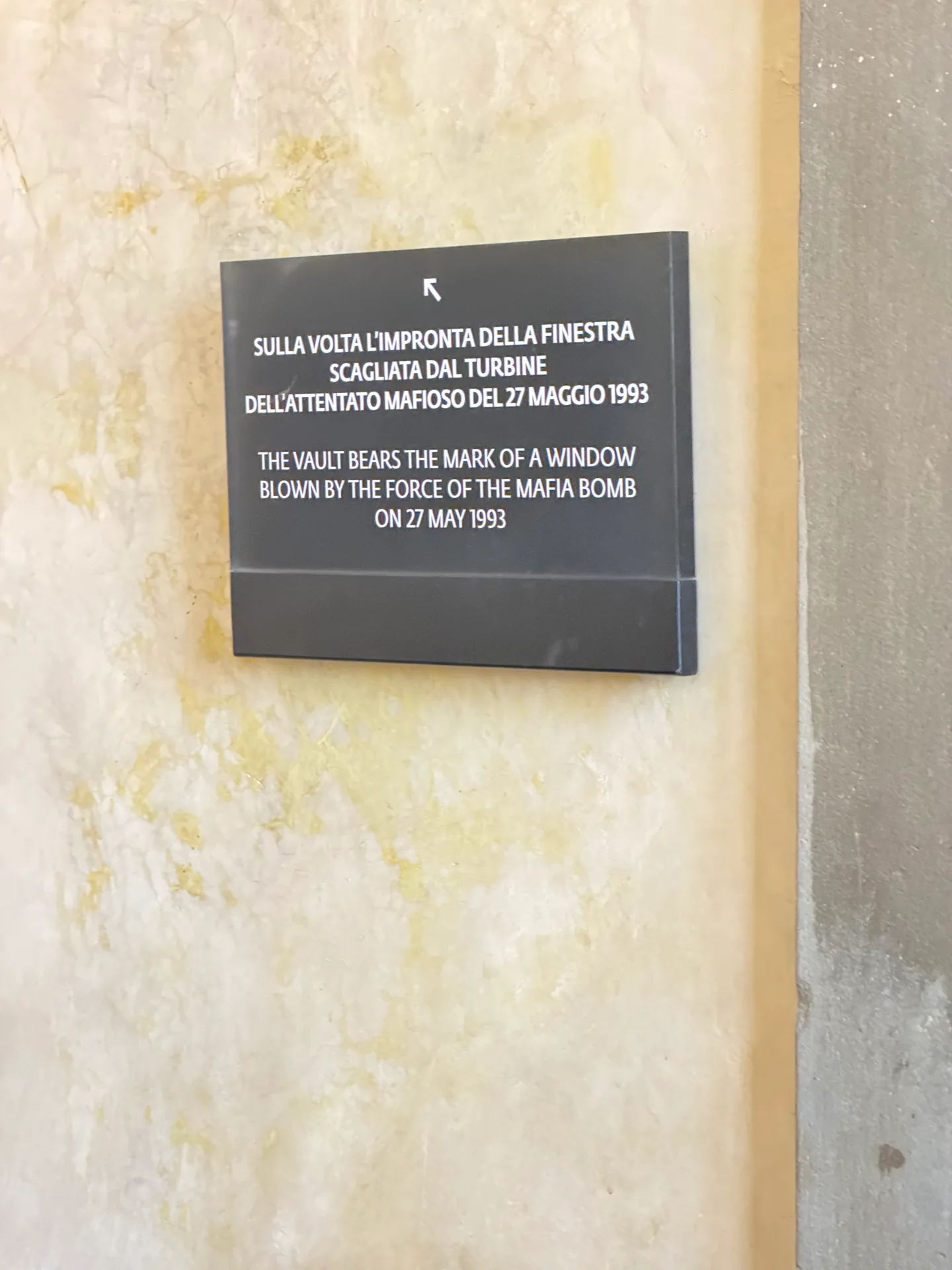 An inscribed plaque mounted on the stairwell wall below the vault.