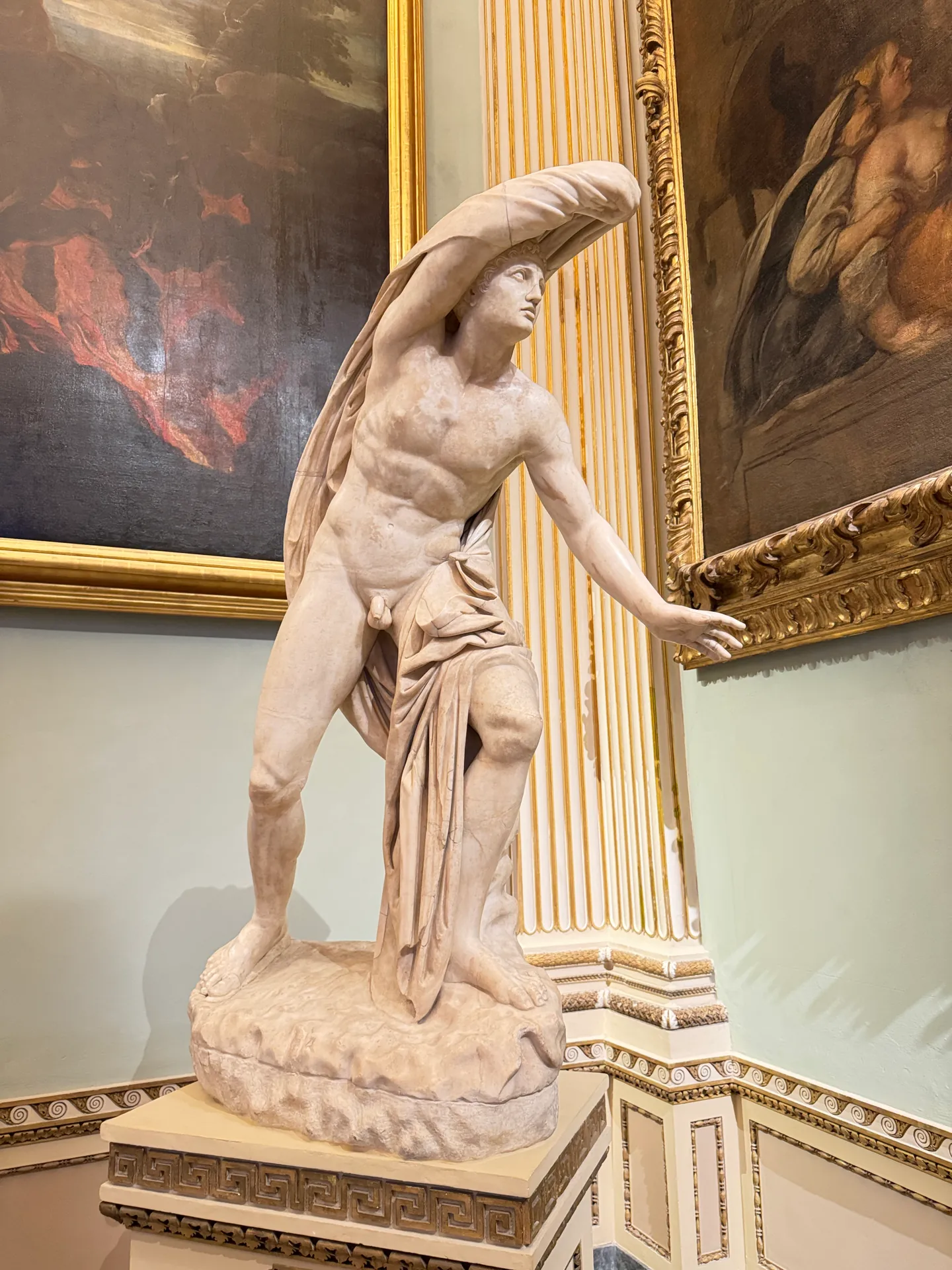 A striding nude son of Niobe with drapery over one arm, clear of the pilaster behind.