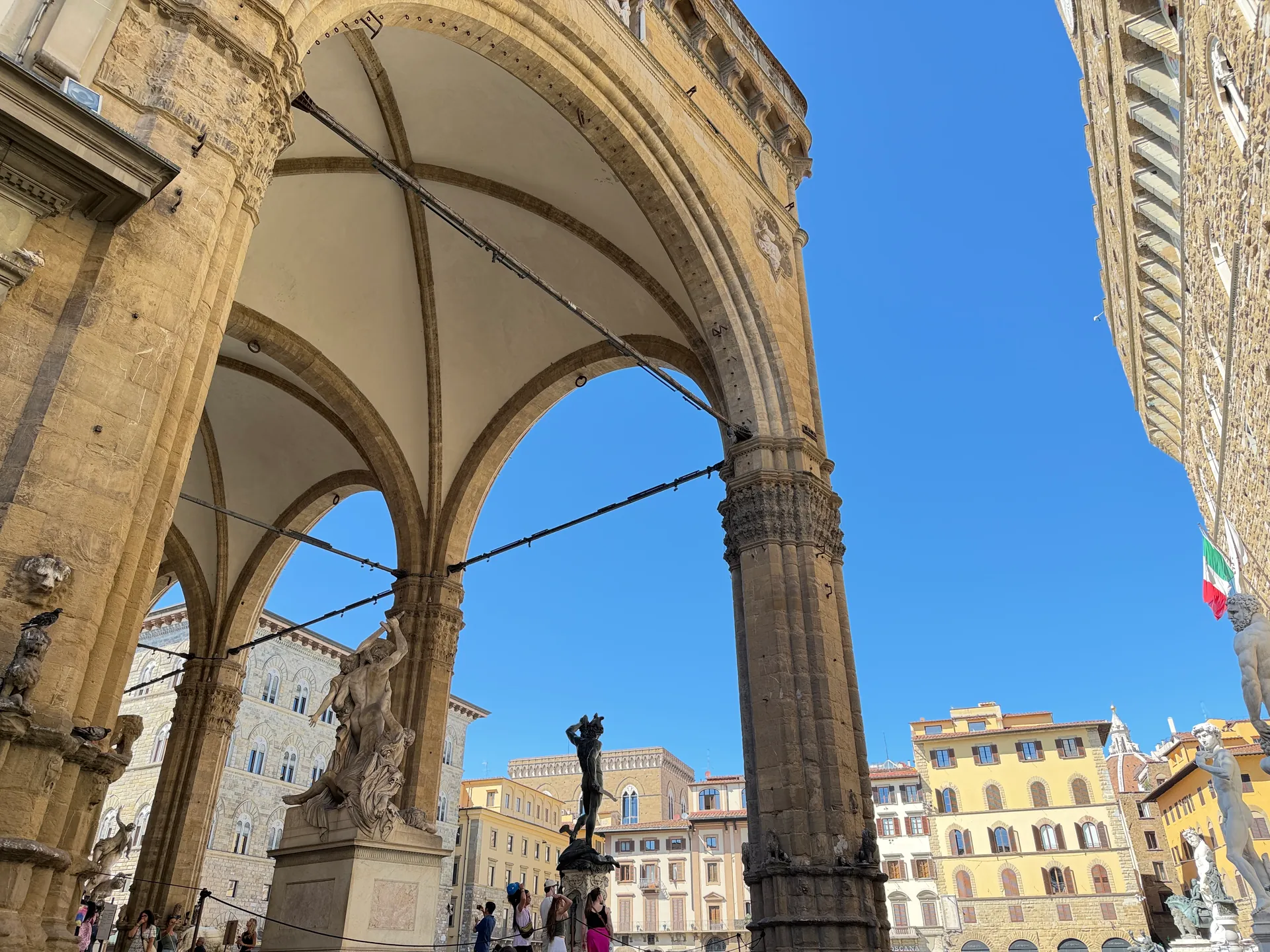 Two tall arches at the north end of the Uffizi courtyard opening onto Piazza della Signoria.