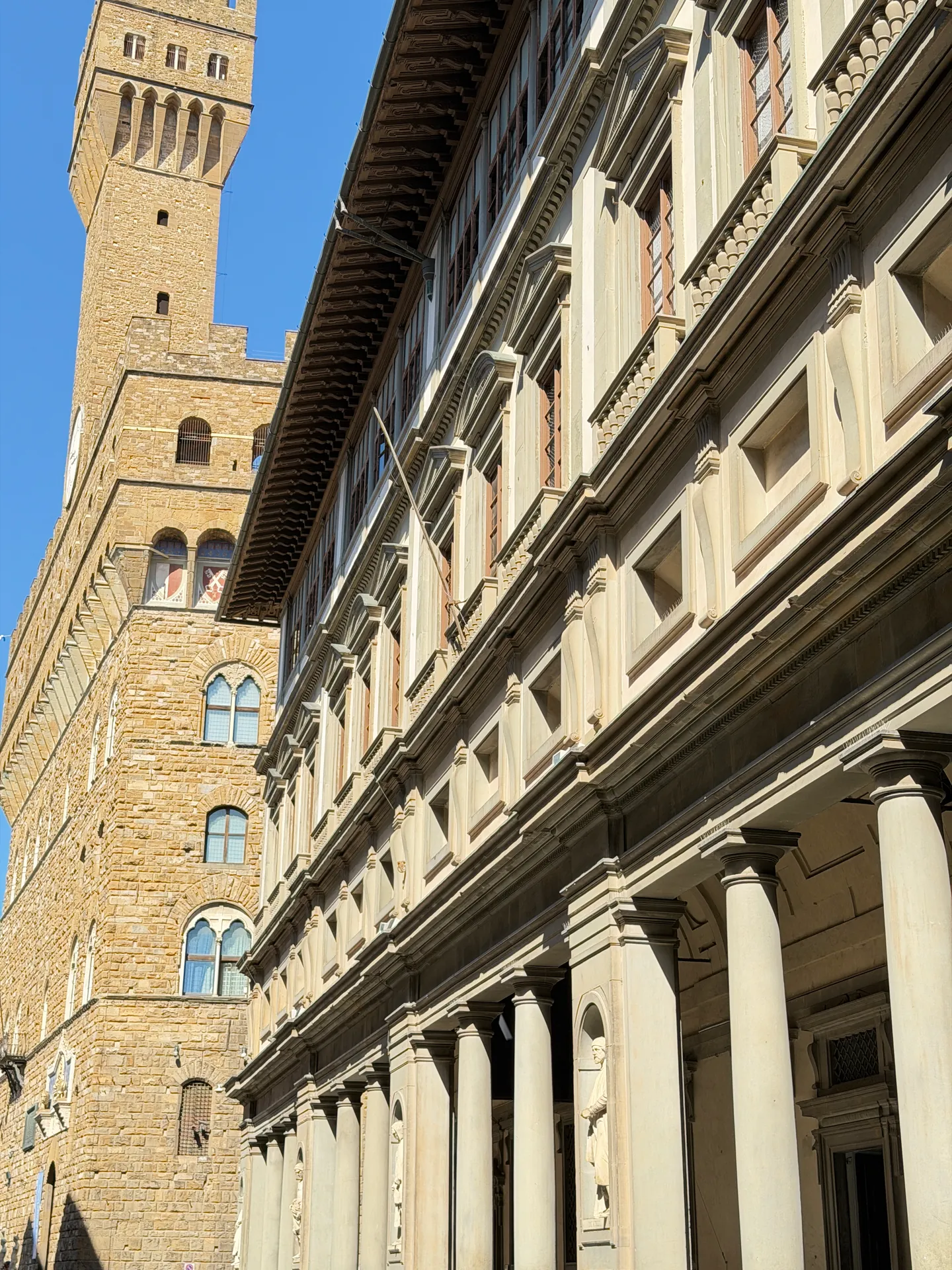 The Uffizi's long west wing with the Torre di Arnolfo of the Palazzo Vecchio rising beyond its cornice.