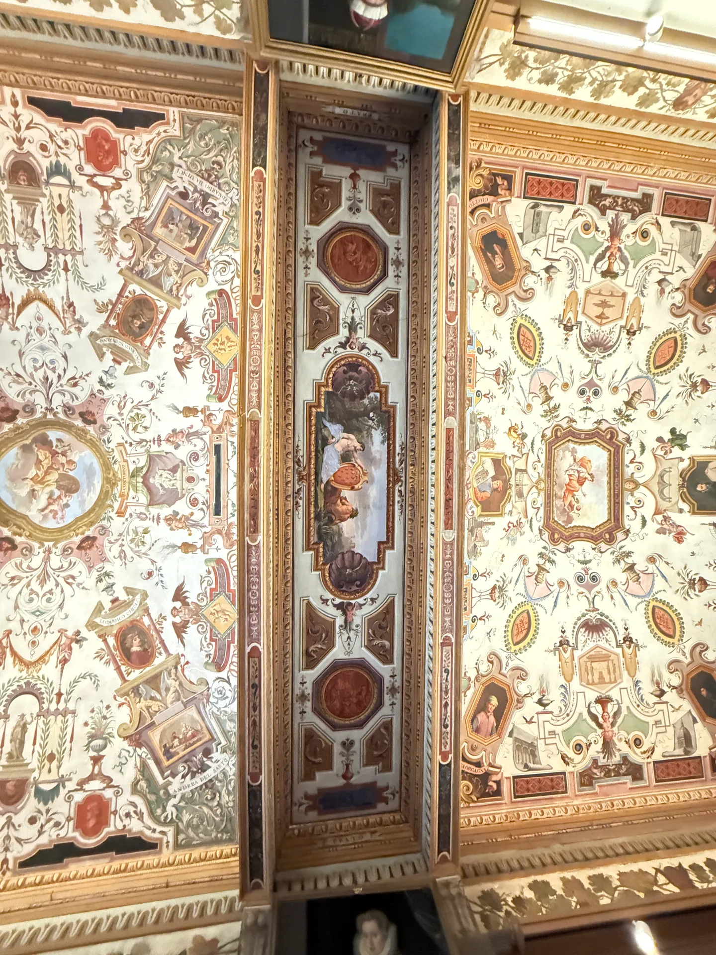 Painted figures worked into the grotesque ornament of a Uffizi corridor ceiling.