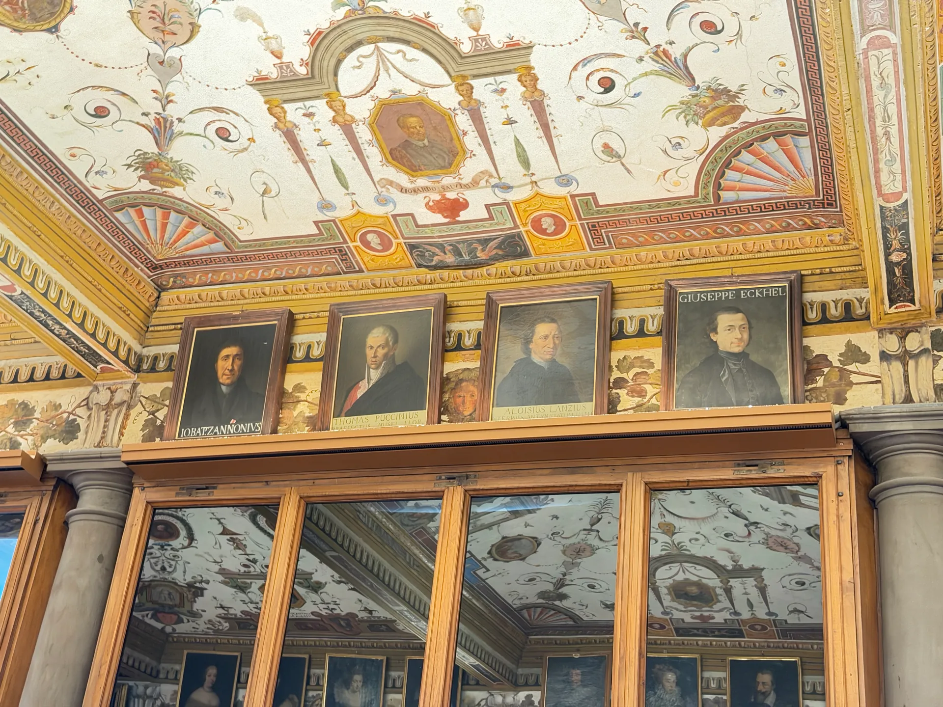 A frieze of small painted portraits running under the grotesque ceiling of a Uffizi corridor.
