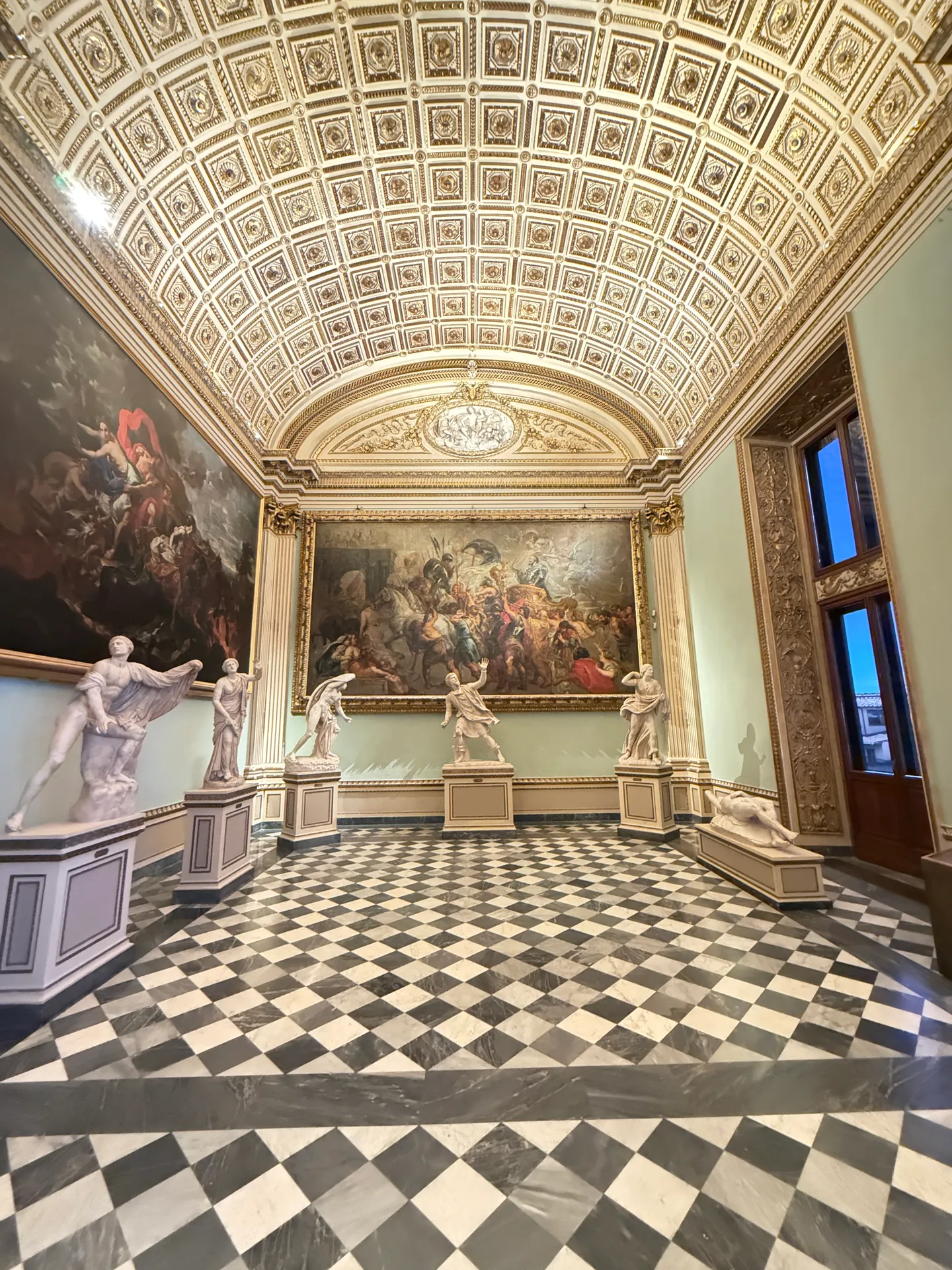 The Sala della Niobe down its axis, the statues ranged along both walls beneath the great canvases.