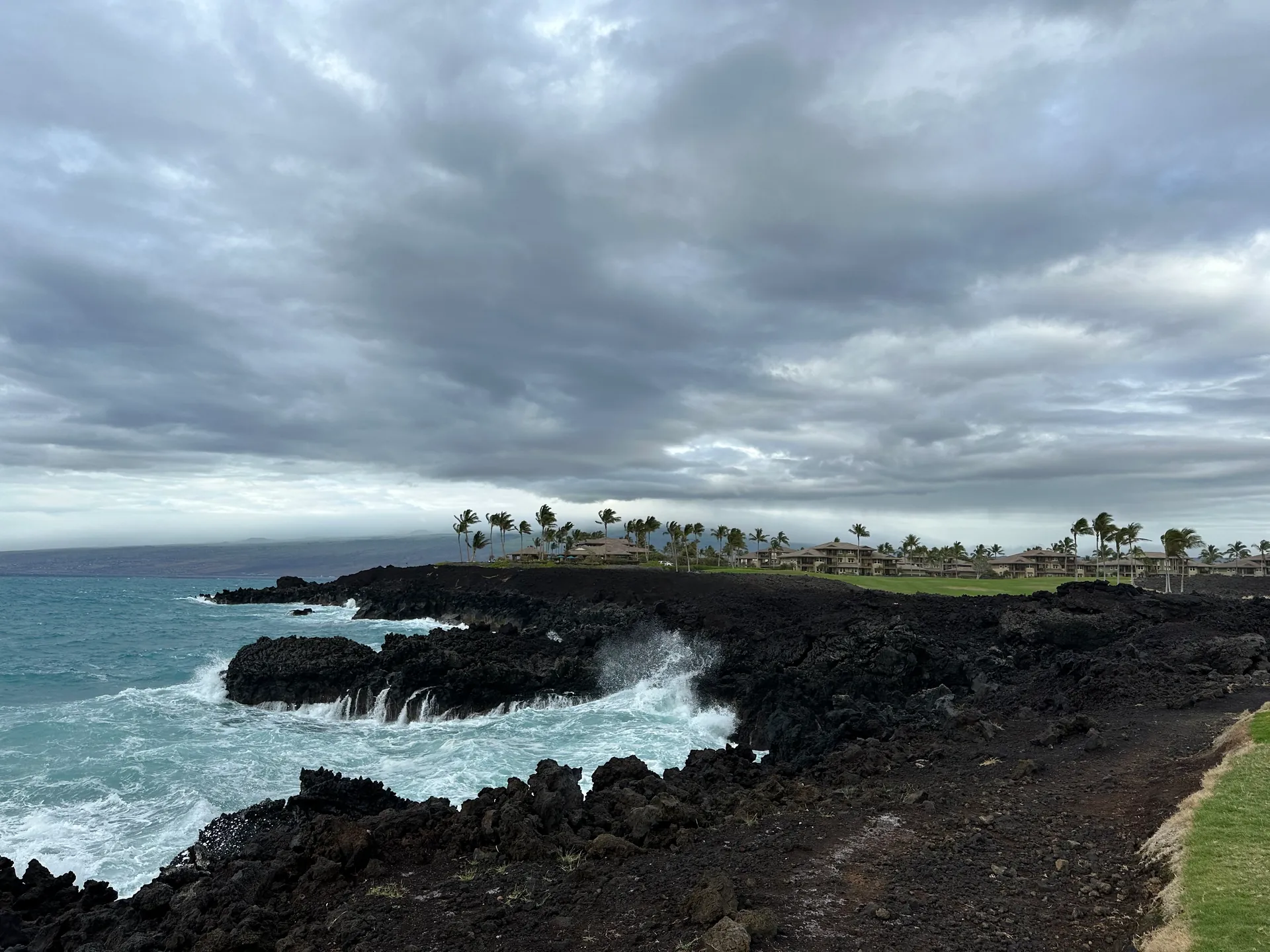 Heavy surf breaking over black lava under grey cloud on the Kohala coast