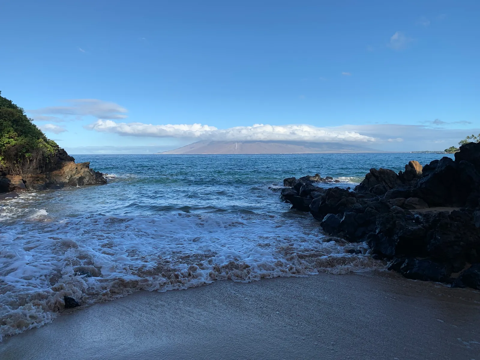 Seawater washing into a small cove between lava rock outcrops