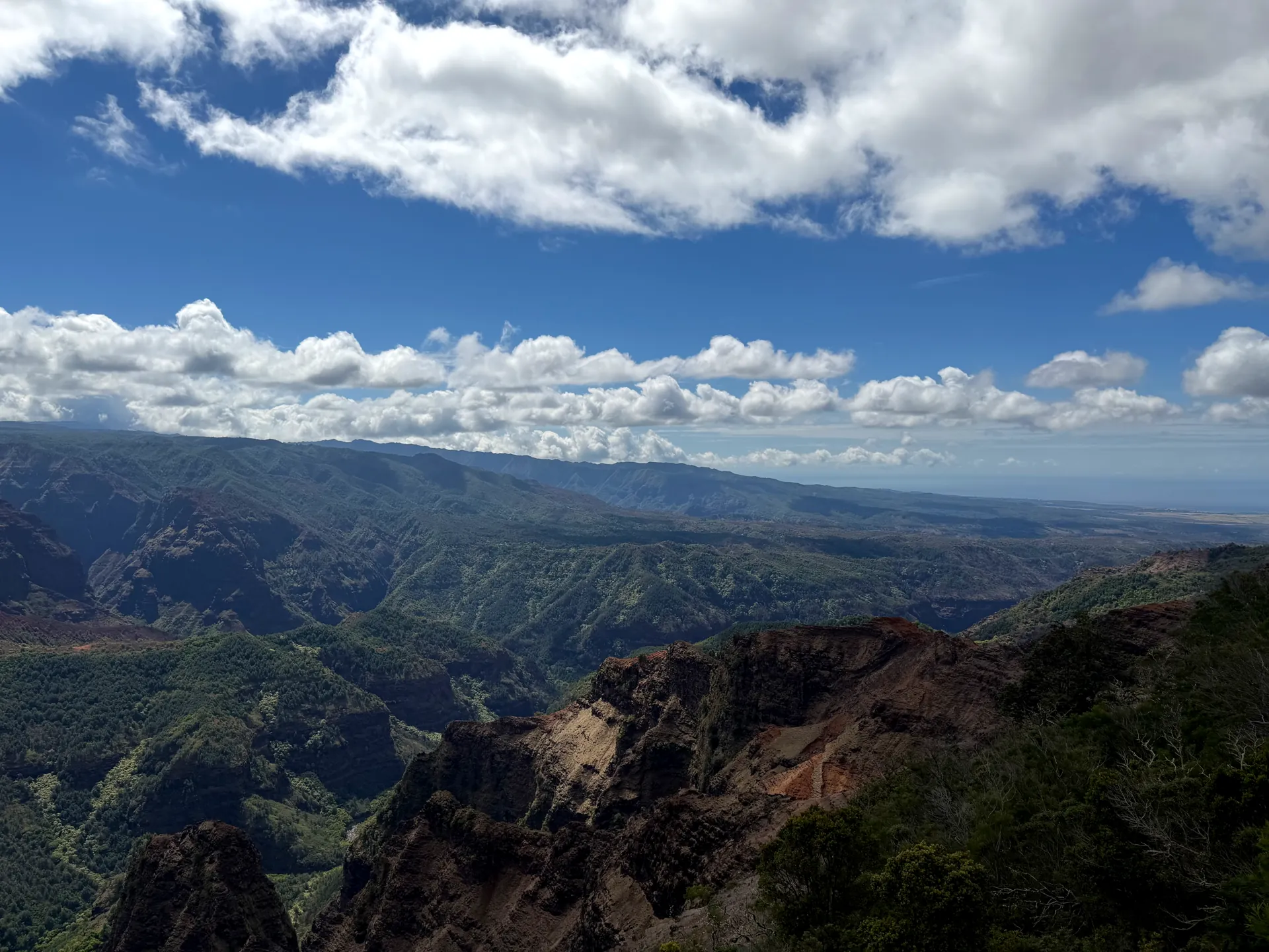 Waimea Canyon looking down toward the distant coast with layered green ridges