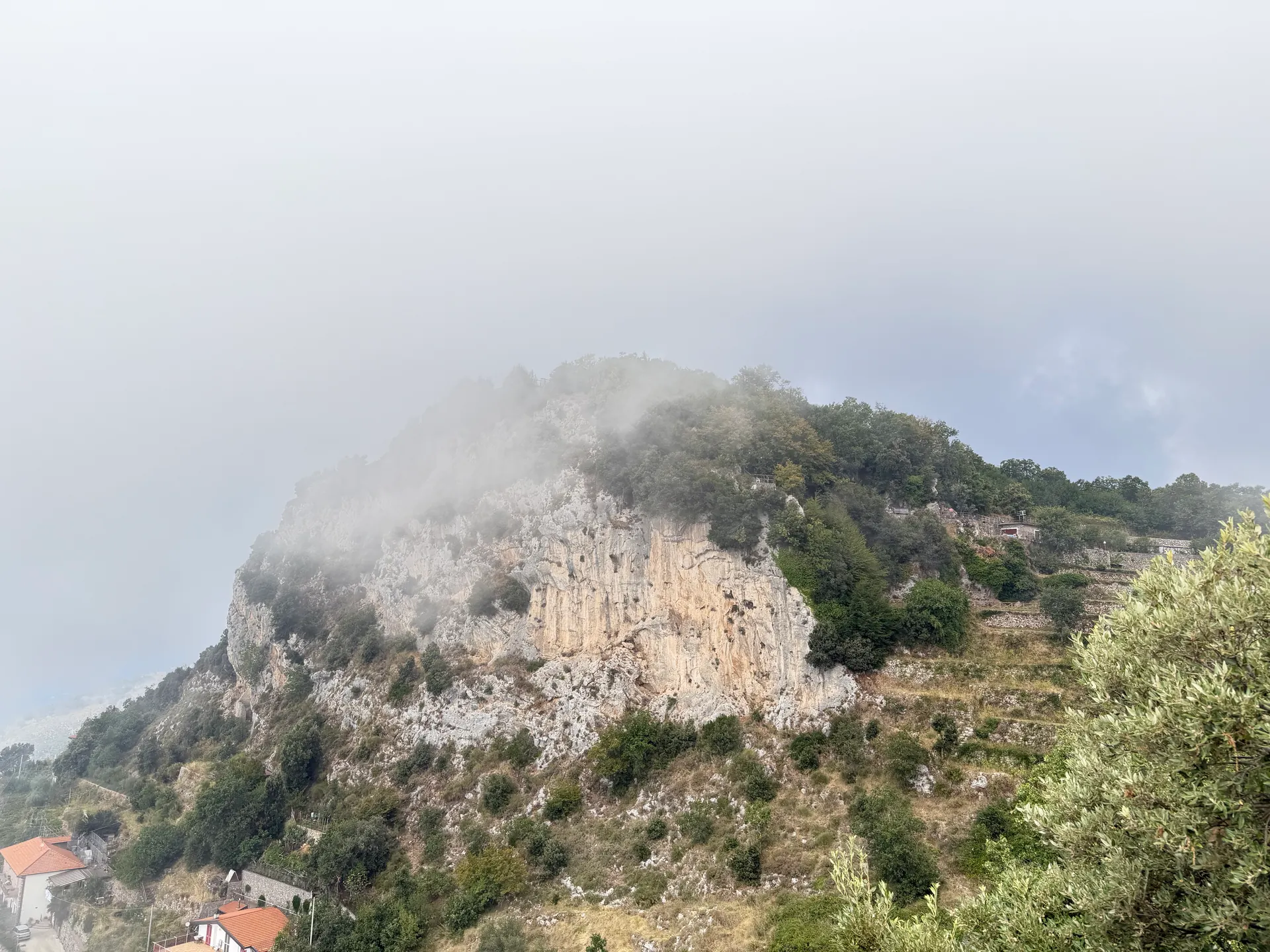 Cloud beginning to cross the shoulder of a limestone crag on a wooded ridge