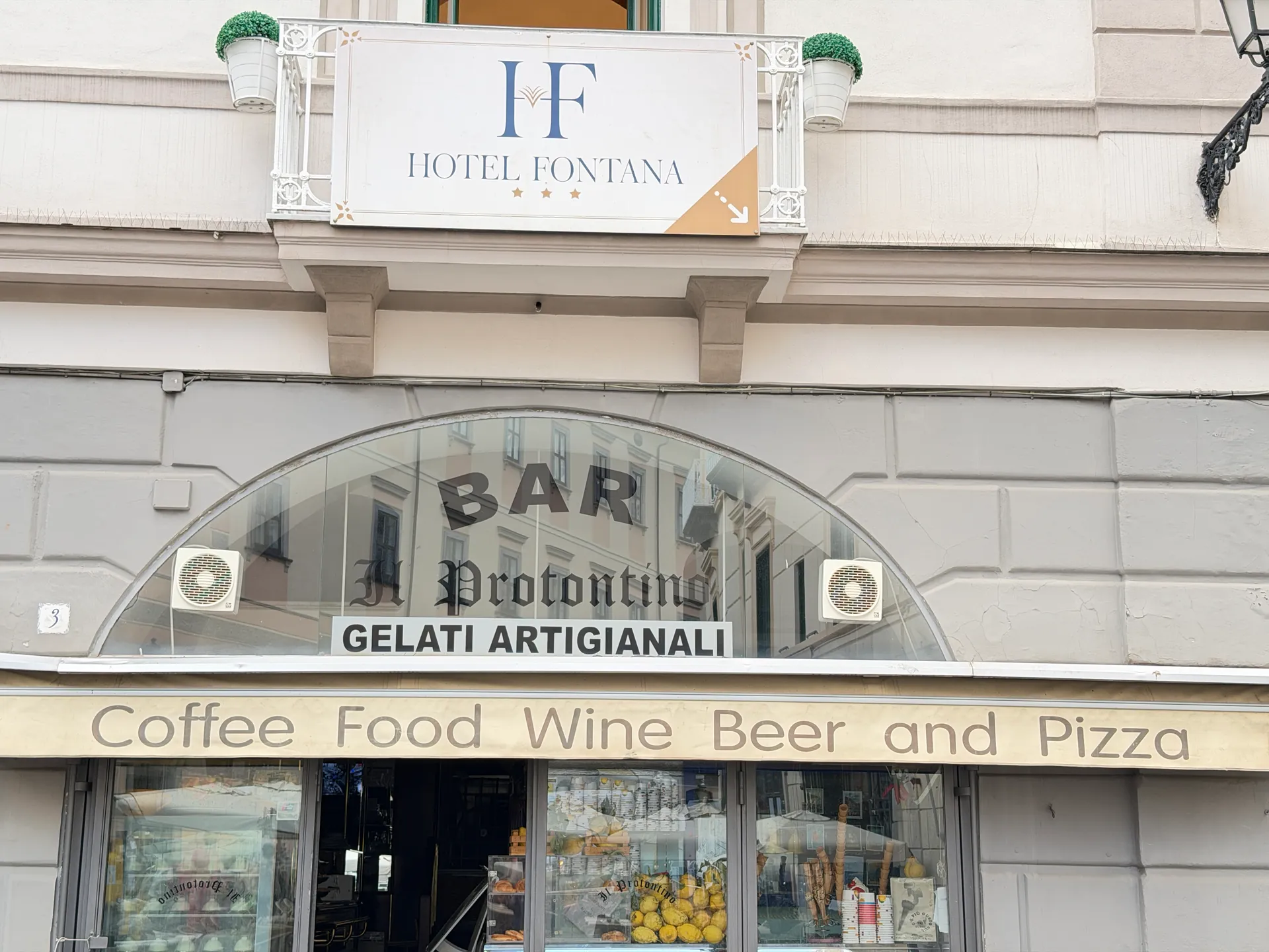 Bar front with an arched glass fanlight reading Bar Il Protontino, below a Hotel Fontana sign