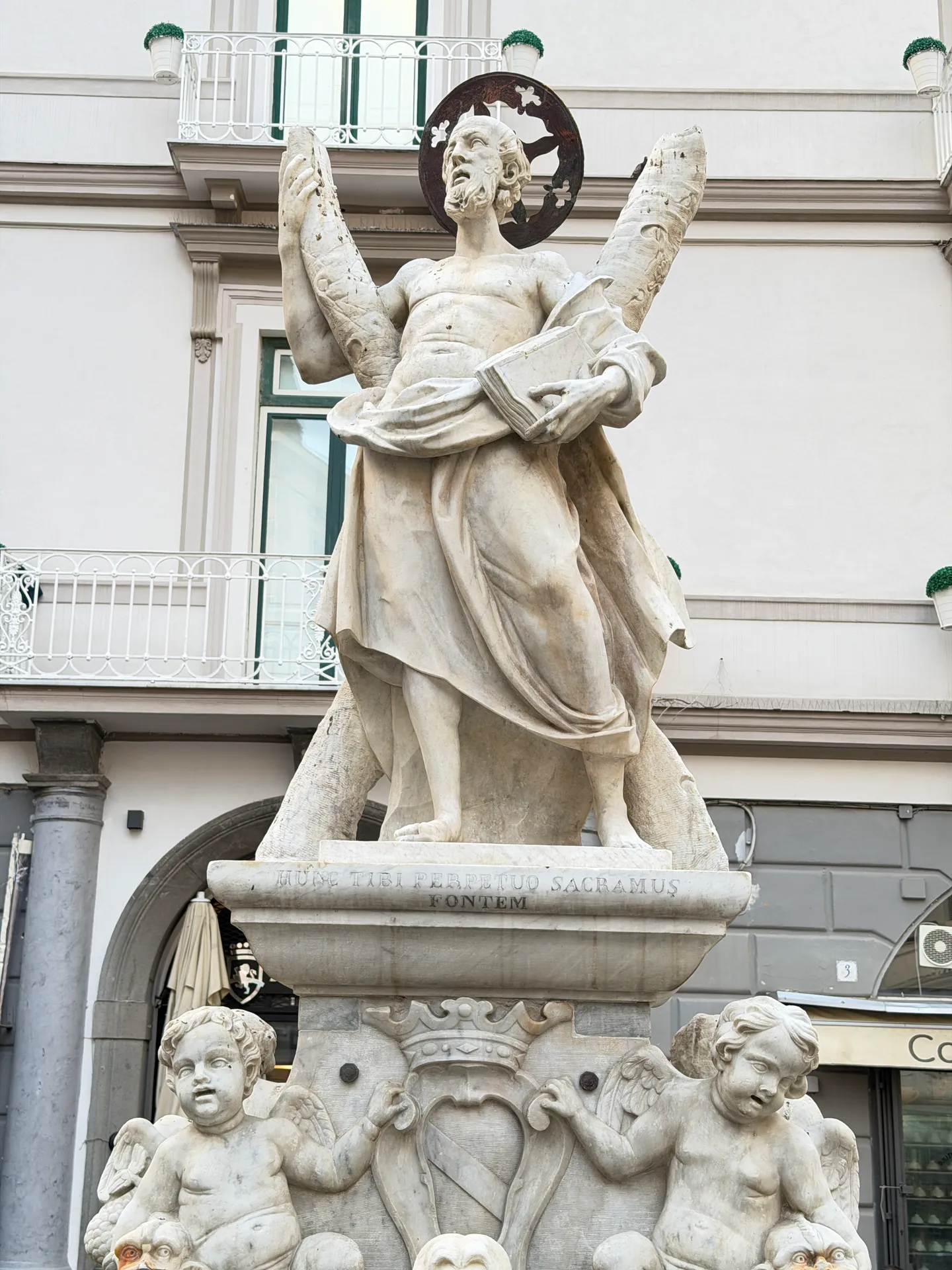 Marble statue of Saint Andrew holding his cross on the inscribed base of the Fontana di Sant'Andrea, cherubs below