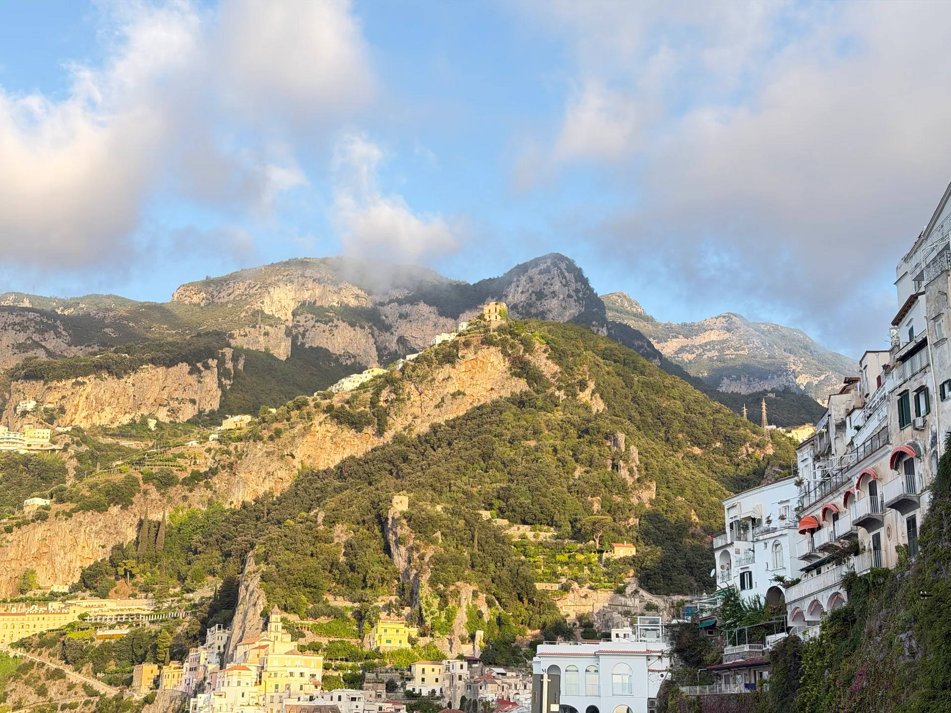 Rocky mountain ridge above the rooftops of Amalfi seen from the coast road with clouds overhead