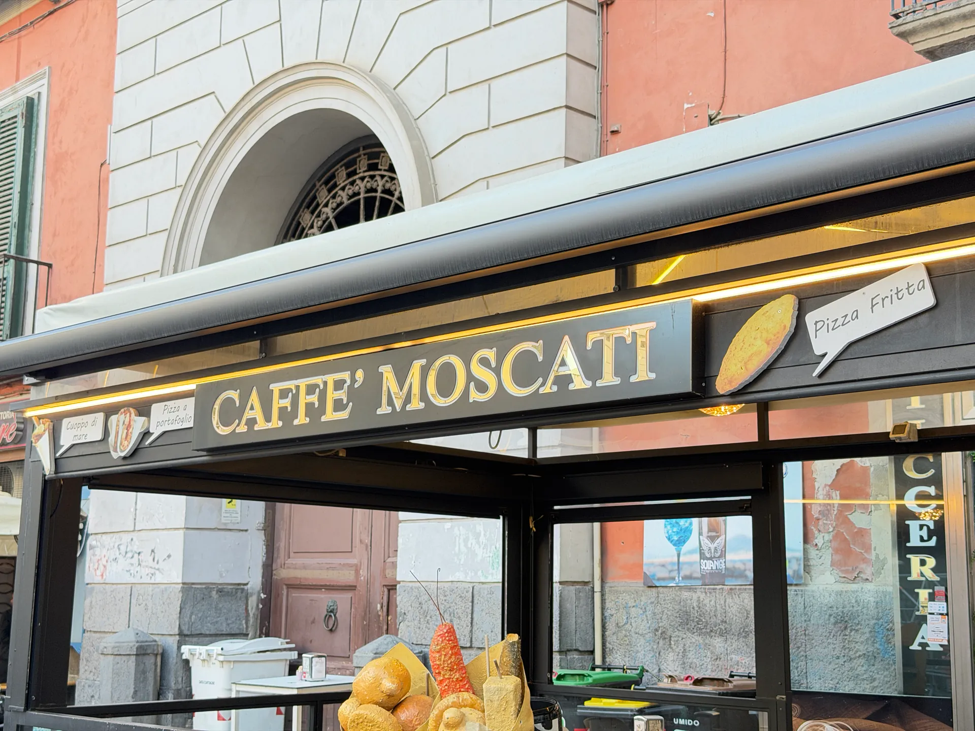 The lit fascia of Caffรจ Moscati on the corner of Piazza del Gesรน Nuovo, Naples
