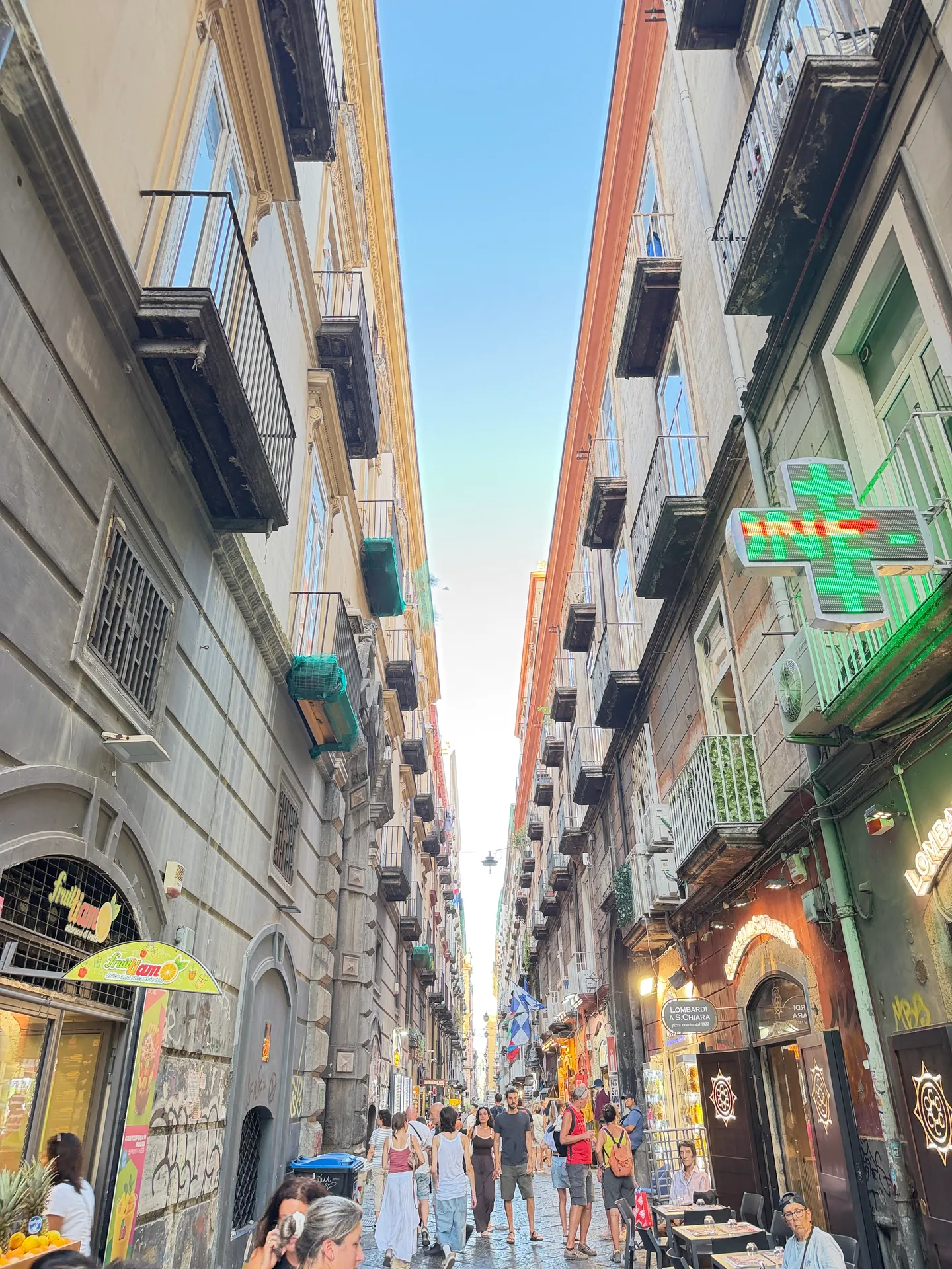 A narrow street in the old centre of Naples crowded with people and shopfronts
