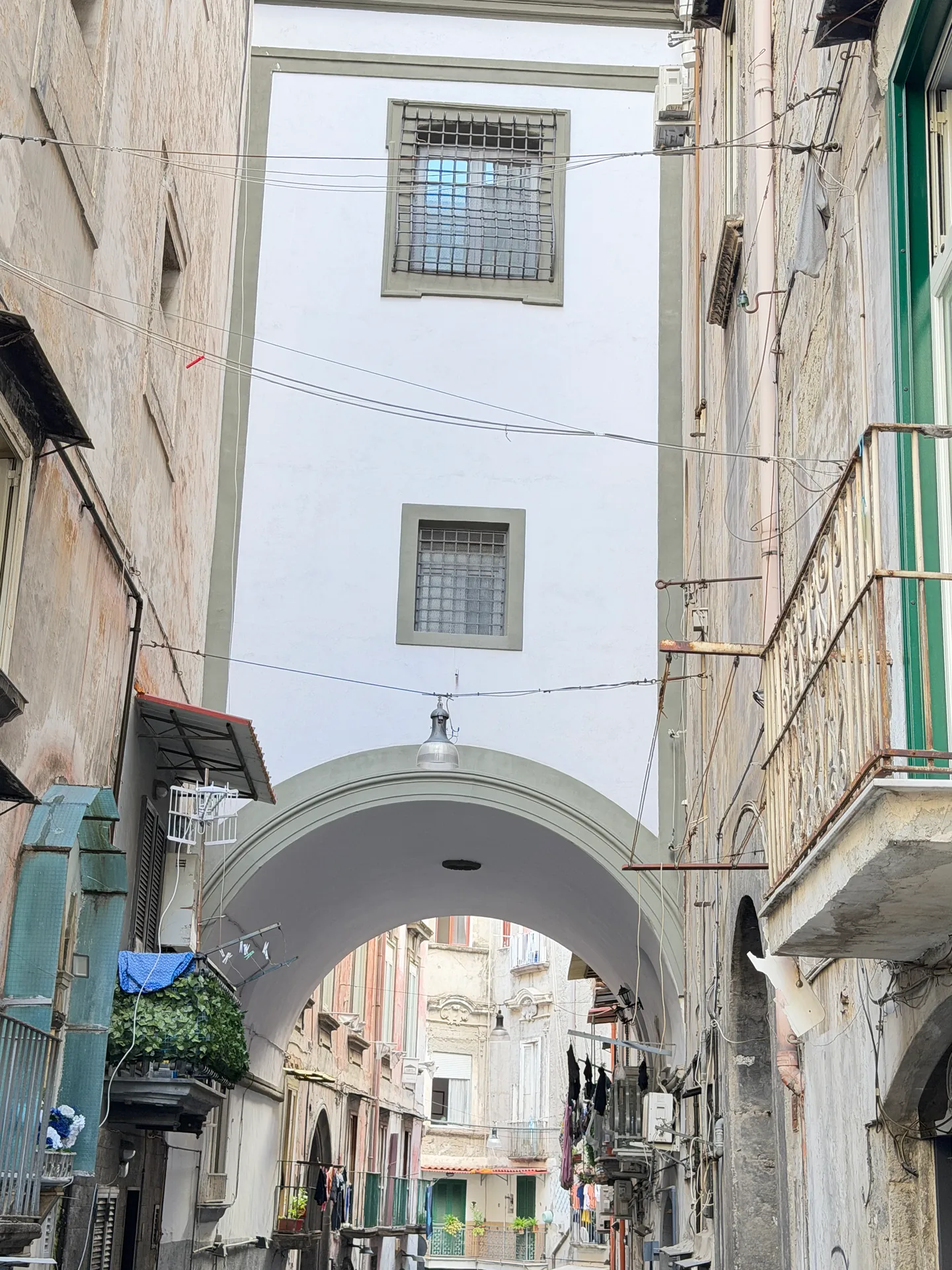 A building spanning a narrow lane on a stone arch in the old centre of Naples