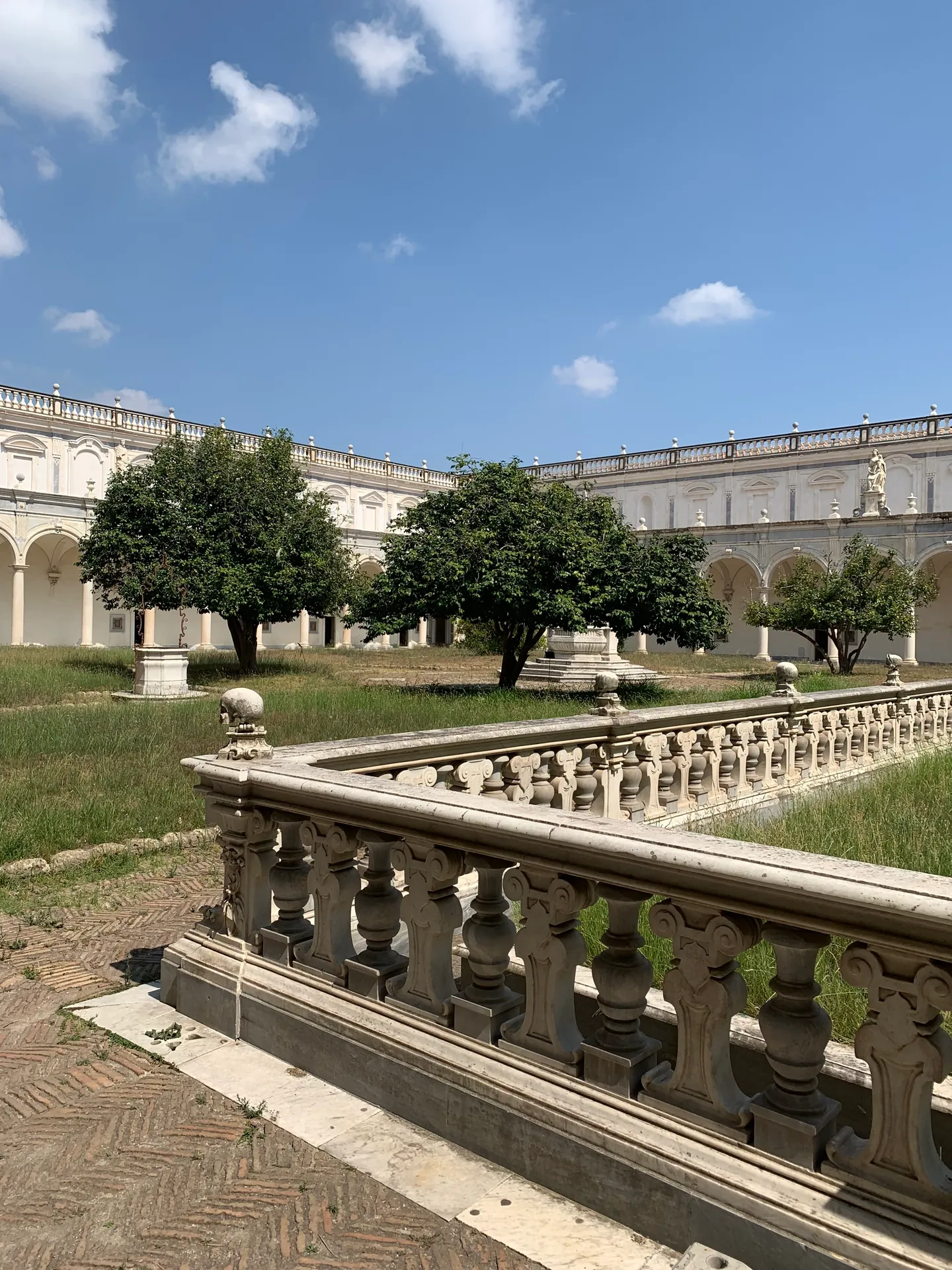A large monastery cloister with orange trees and a stone balustrade in Naples