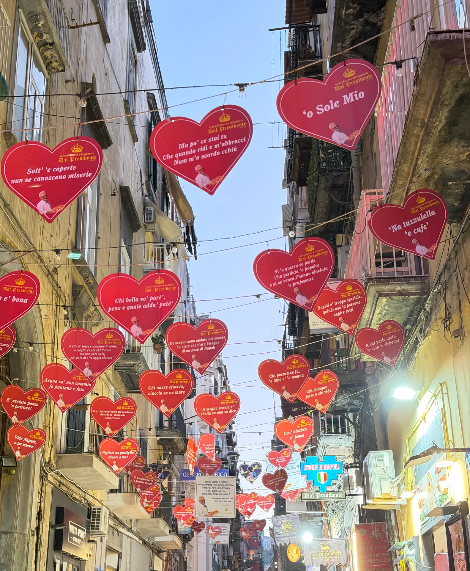 Red hearts printed with Neapolitan sayings strung over a lane in Naples