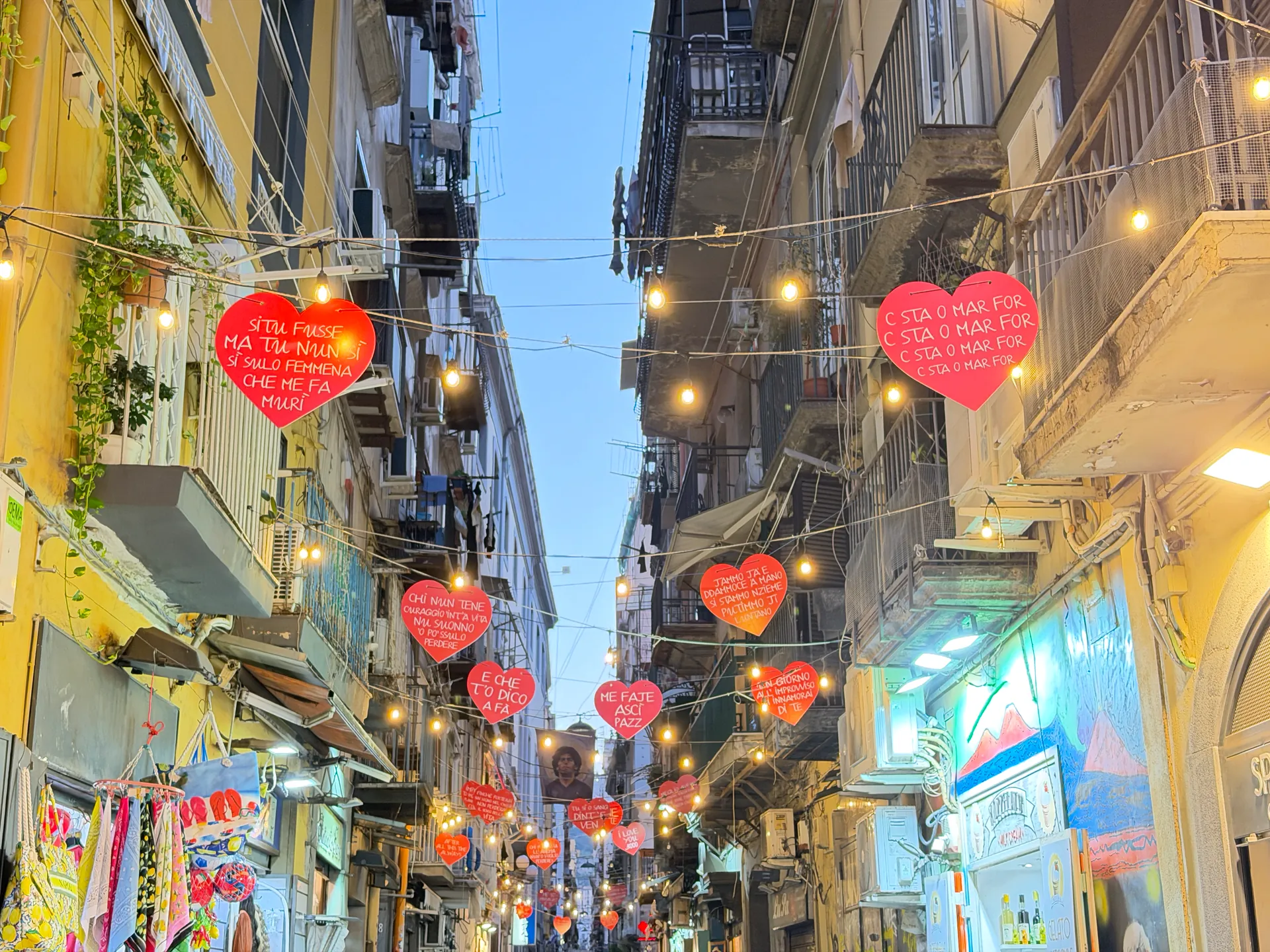 Red hearts and strings of lights above a narrow lane in the old centre of Naples
