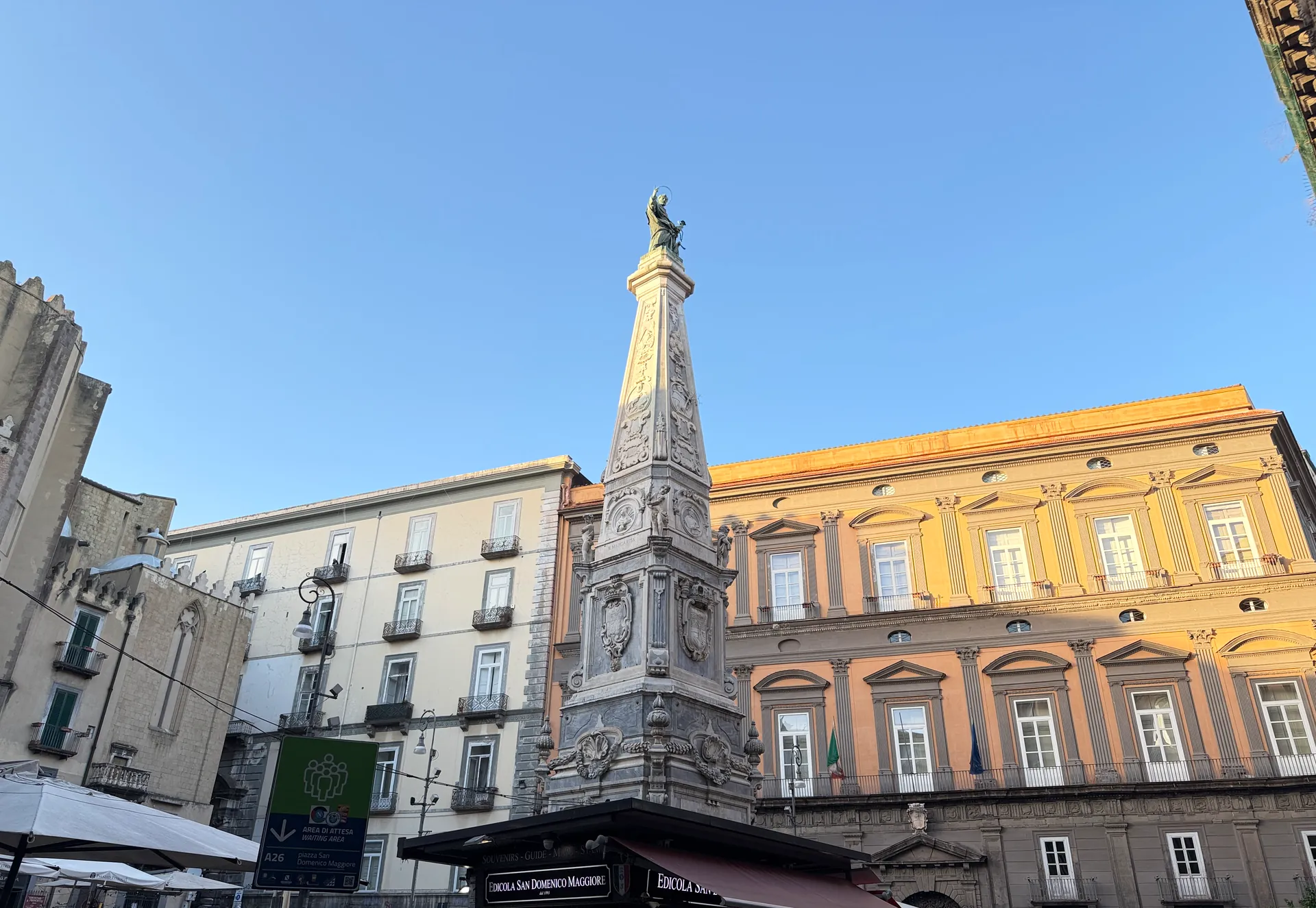 The obelisk in Piazza San Domenico Maggiore above the kiosk awning, Naples