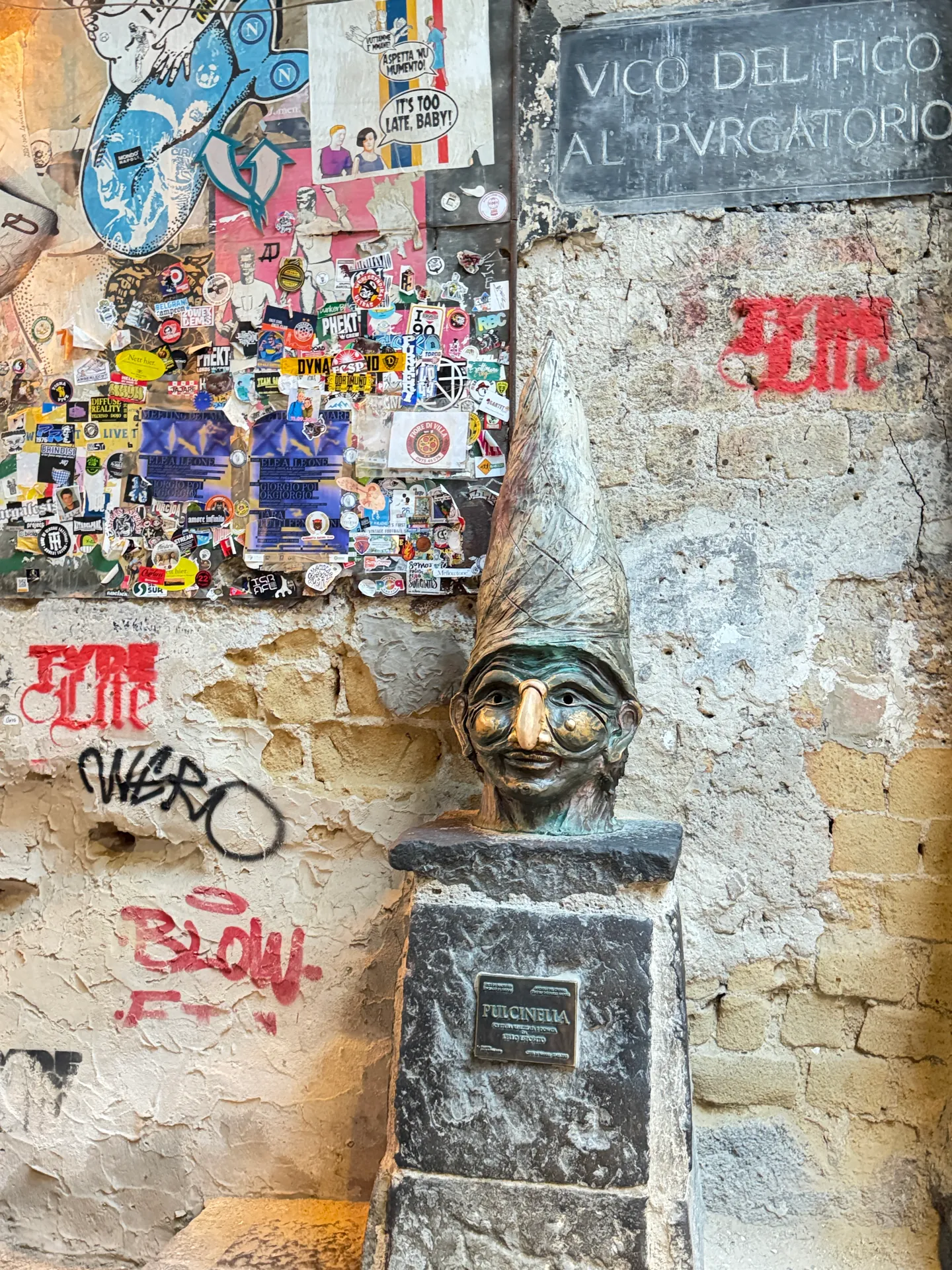 A bronze Pulcinella head on a plinth at Vico del Fico al Purgatorio, Naples
