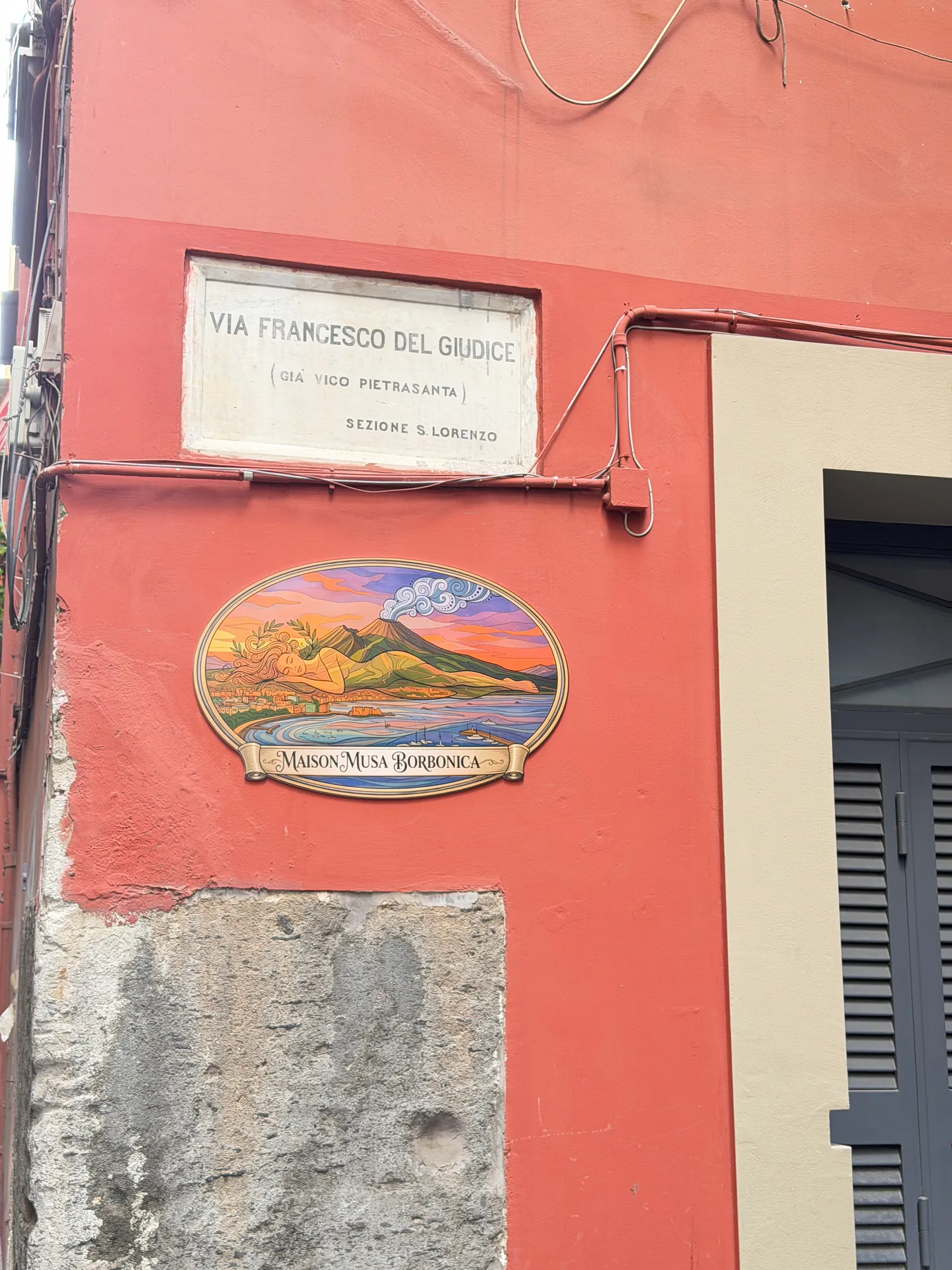 A marble street plate reading Via Francesco del Giudice above a painted majolica oval, Naples