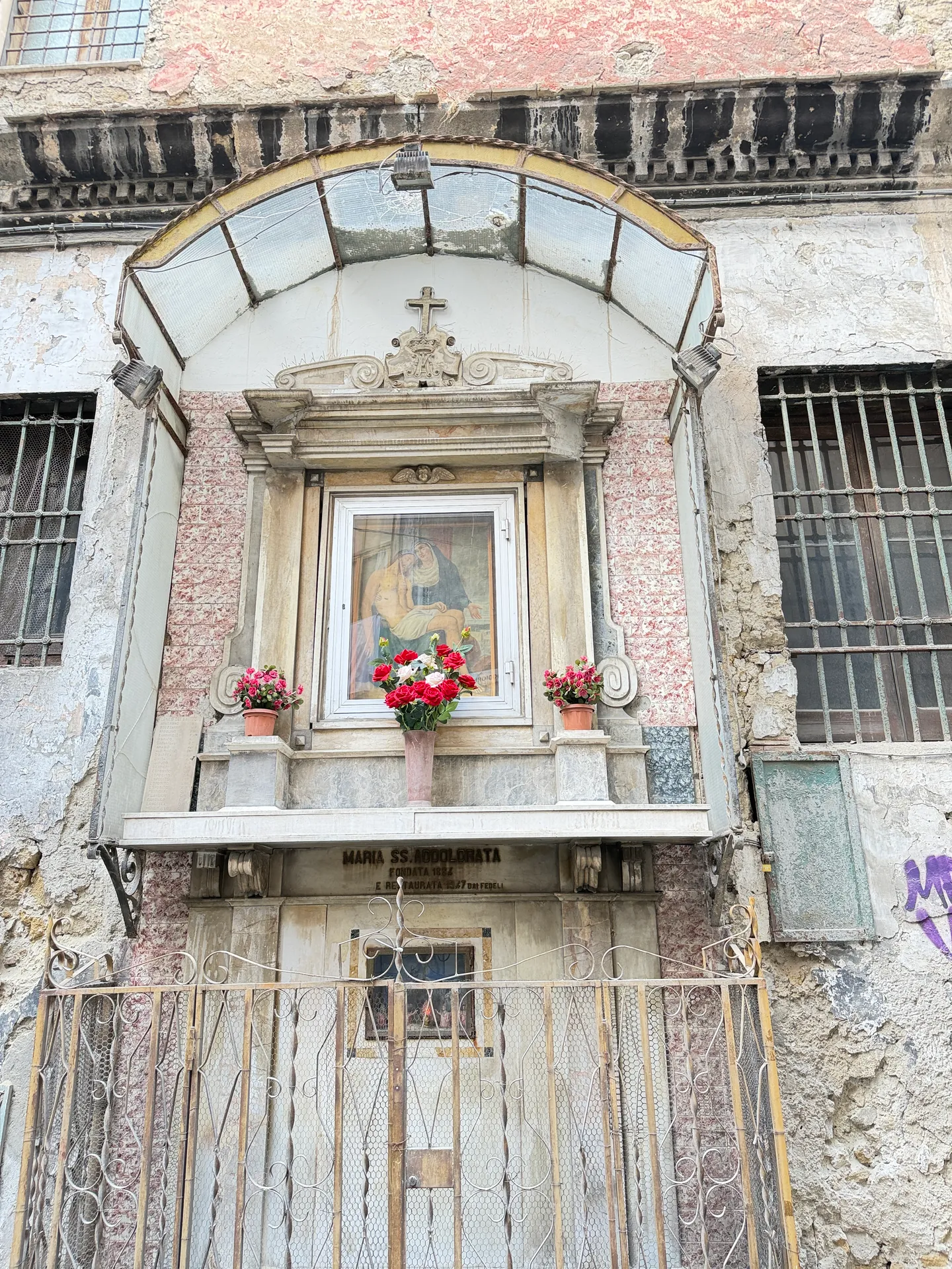 The Maria SS. Addolorata shrine with flowers on its ledge in a street front, Naples