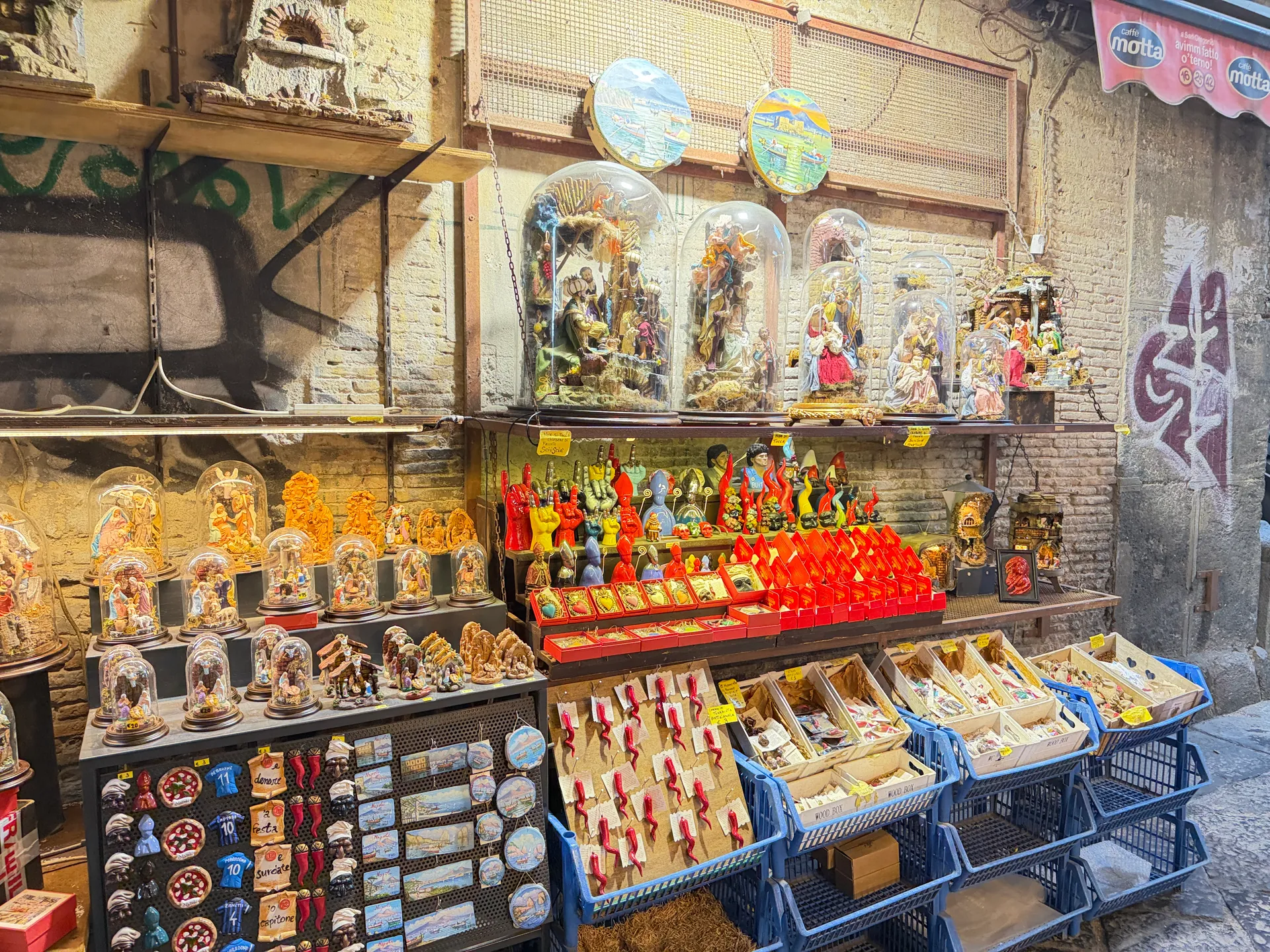 Nativity scenes under glass domes above trays of horn charms on San Gregorio Armeno