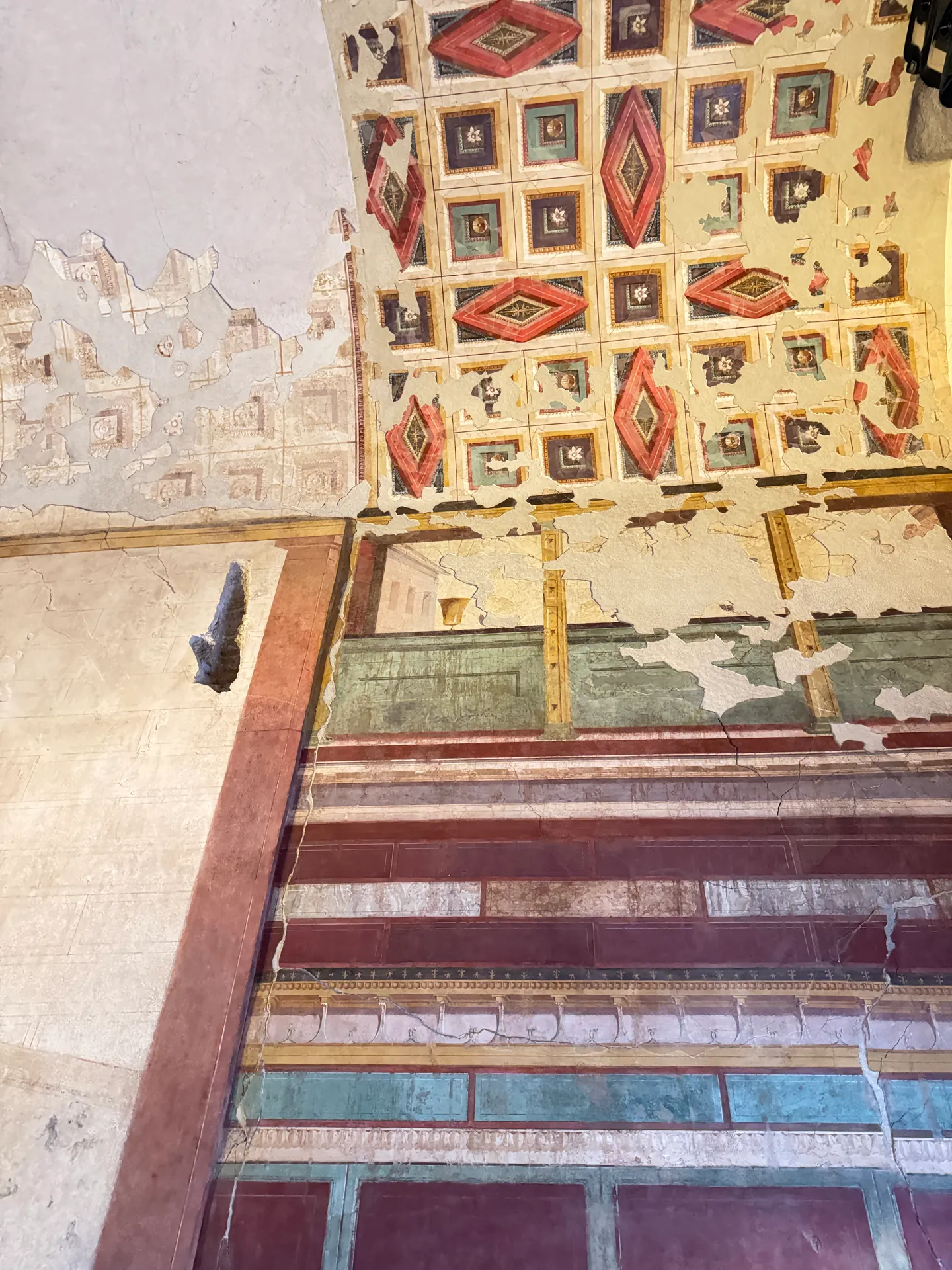 Coffered painted ceiling in the House of Augustus, red lozenges and small figures in yellow frames.