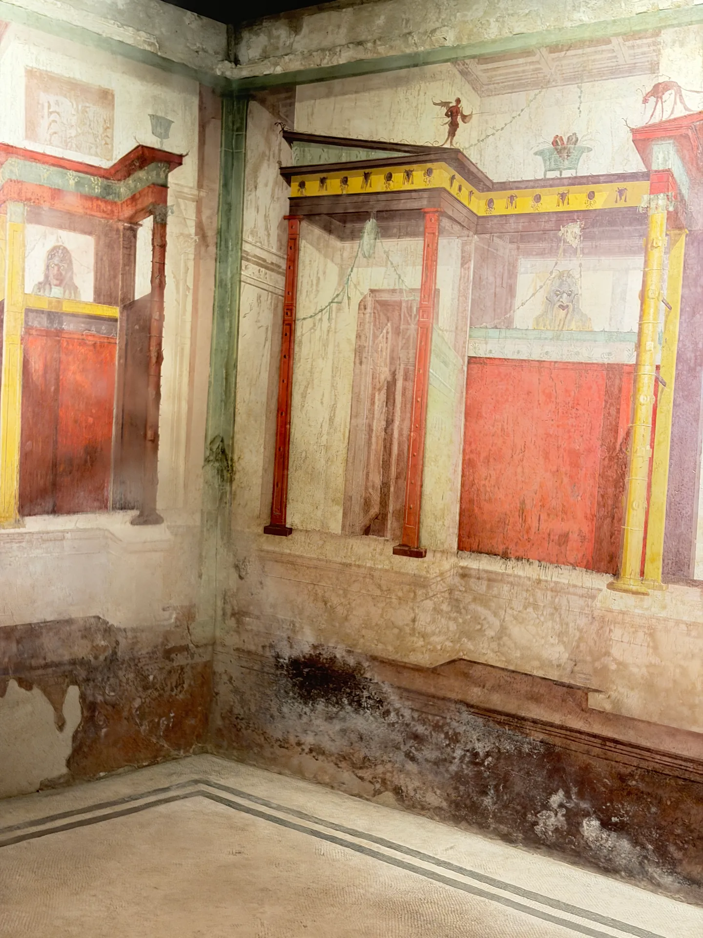 Corner of a painted room in the House of Augustus, red panels and slender columns on both walls.