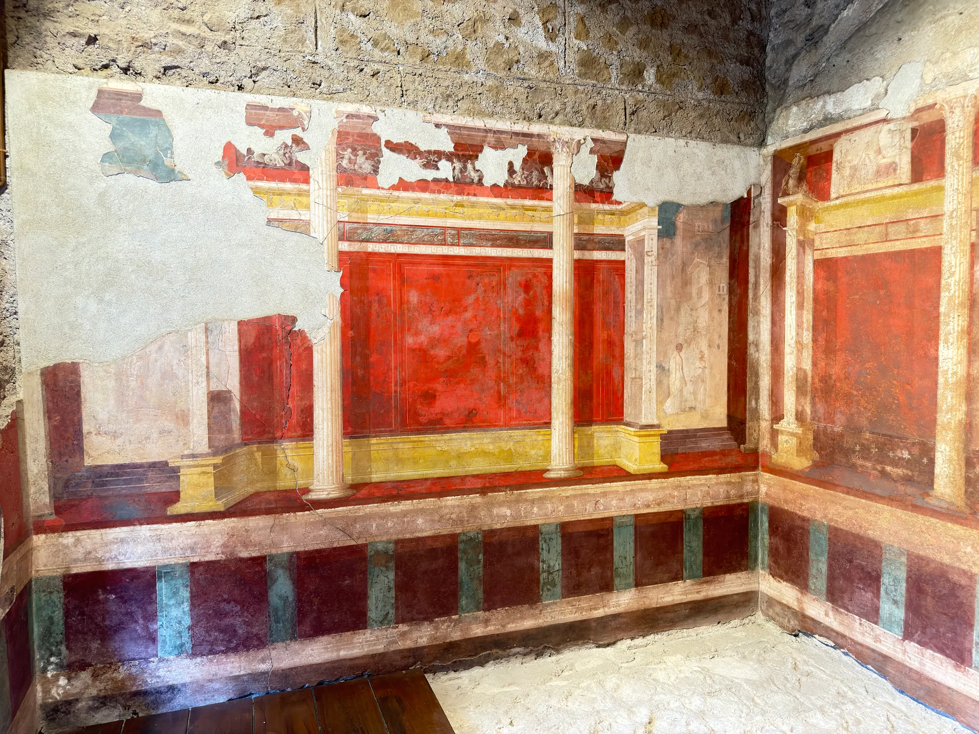 Painted room in the House of Augustus, red panels between slender columns above a striped dado.