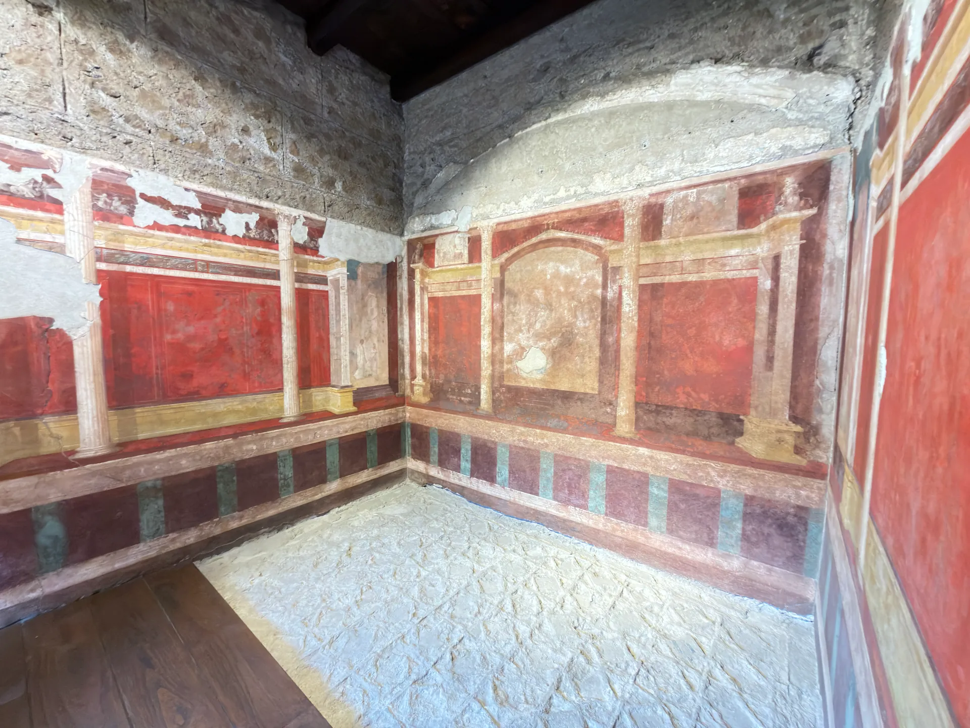 Painted room in the House of Augustus in plain light, red panels and an arched central panel.